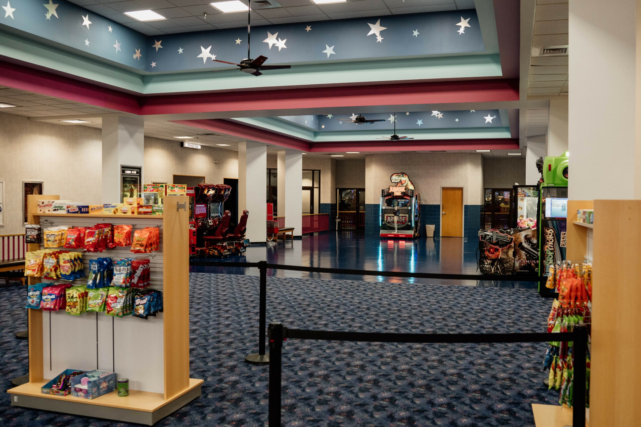 Empty store with shelves of snacks and toys, ceiling decorated with stars, and a blue carpeted floor.
