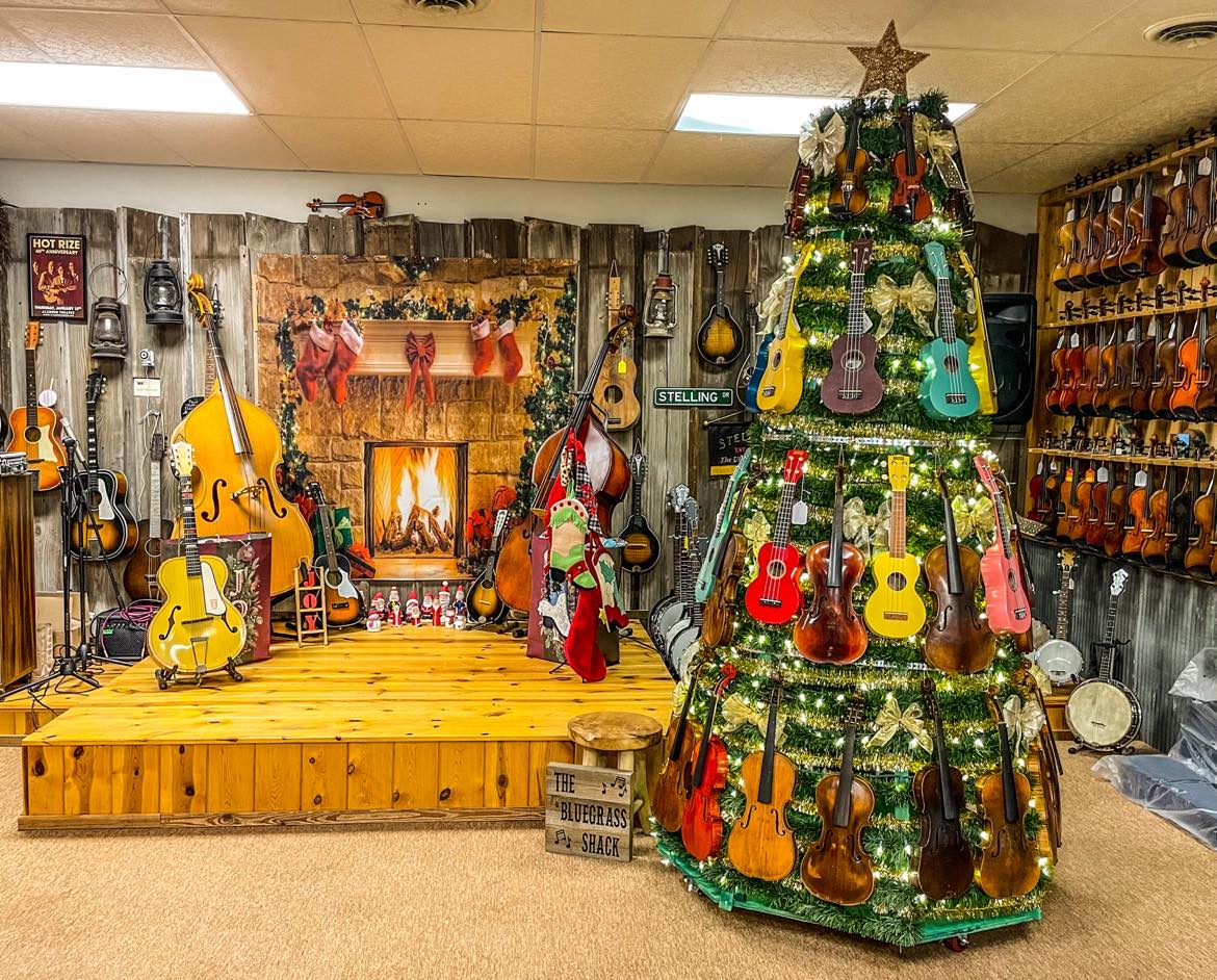 Display with guitars, a decorated Christmas tree with guitars, and a person in a red and white outfit.