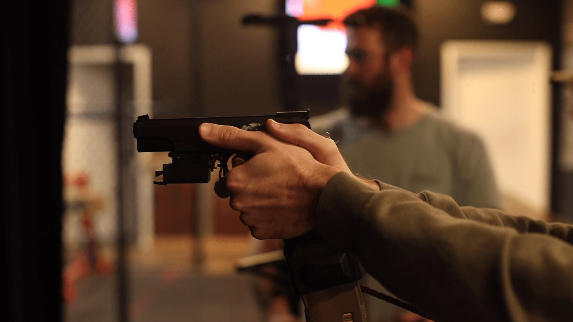 Person holding a handgun with a blurred background, indoors, focus on hands and gun.