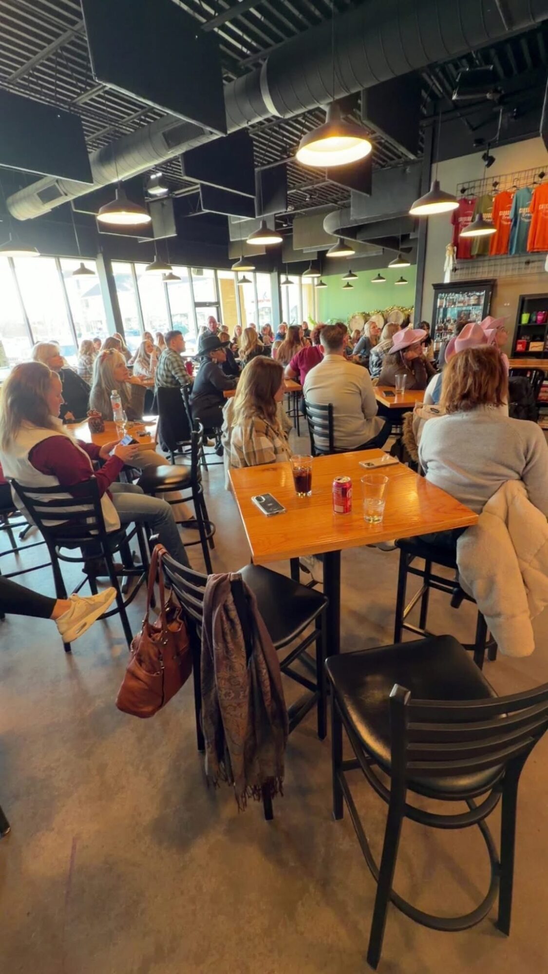 People seated at tables in a brightly lit cafe or restaurant with large windows and colorful decor.