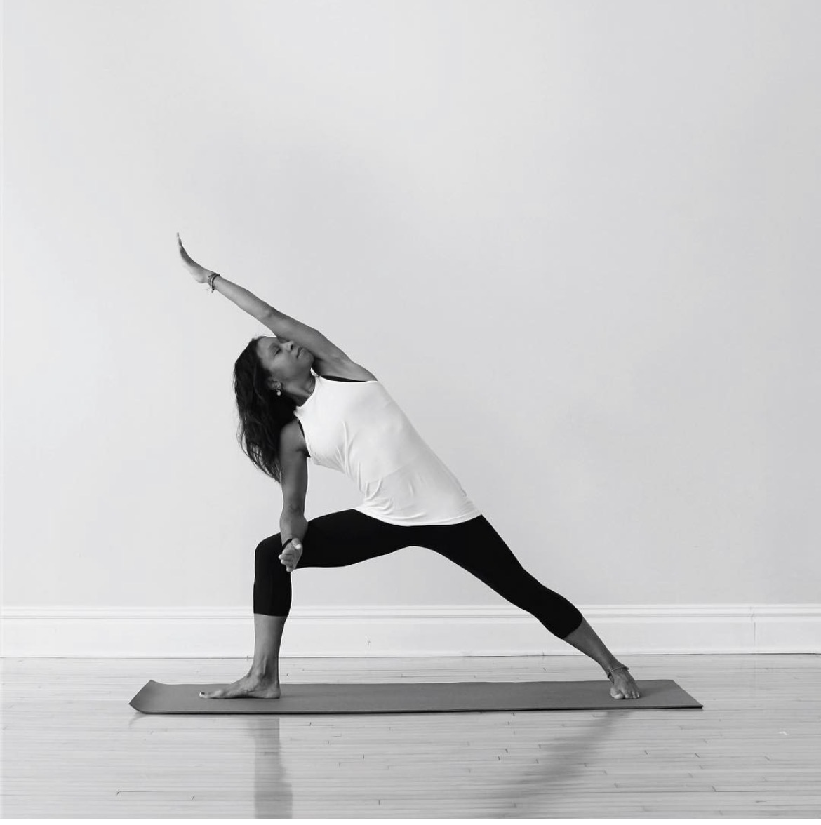 Person practicing yoga in a side stretch pose on a mat against a plain wall.