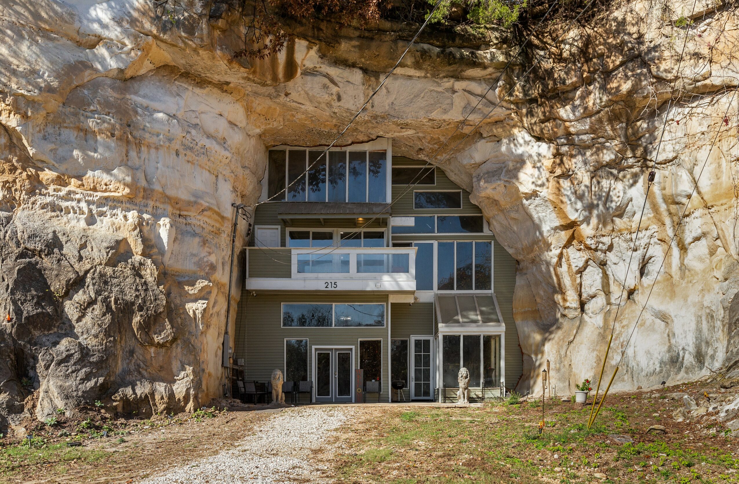 Modern building built into a large rock formation with multiple glass windows and doors, surrounded by natural landscape.