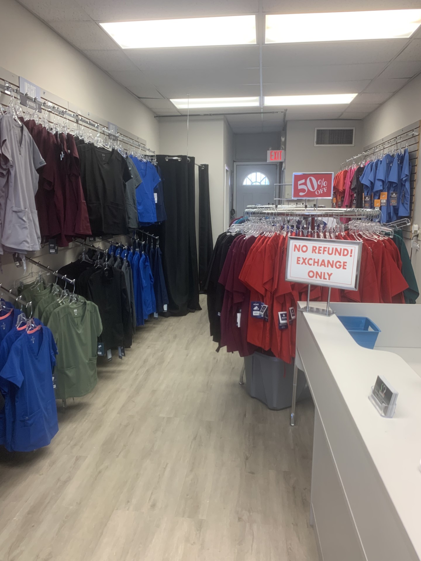 Clothing store interior with racks of shirts and pants, and a checkout counter on the right.
