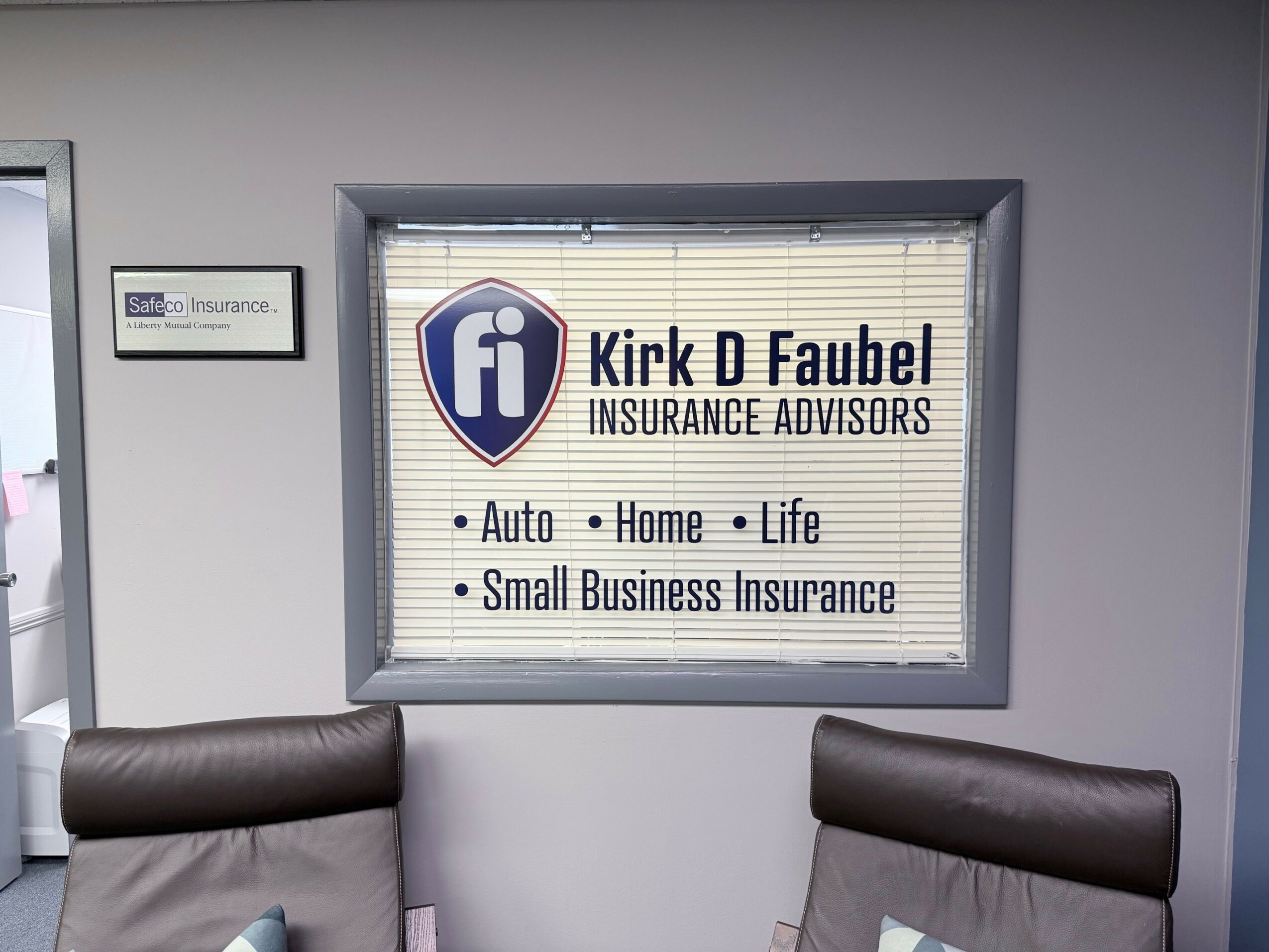 Signboard for Kirk D Faubel Insurance Advisors with logo and services listed, mounted on a wall.