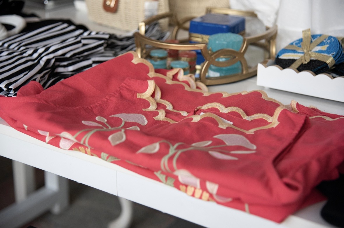 Red fabric with gold and silver decorative elements on a white surface, with other items in the background.