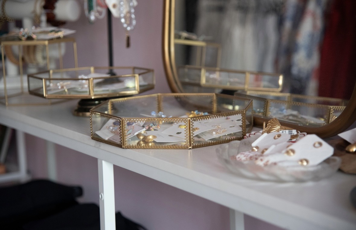 Display of jewelry trays and accessories on a white table with a mirror in the background.