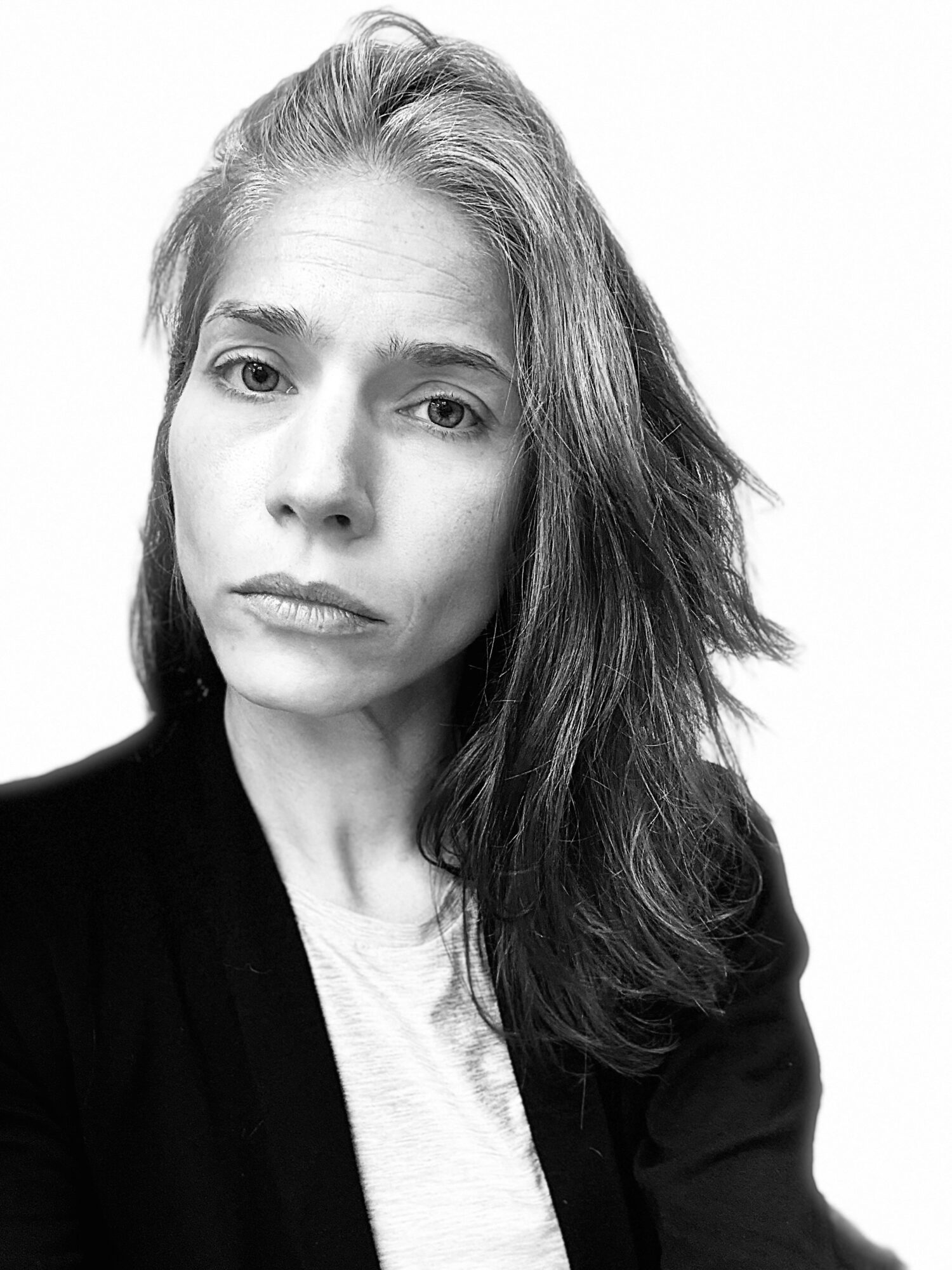 Portrait of a woman with long hair, looking directly at the camera, in black and white.