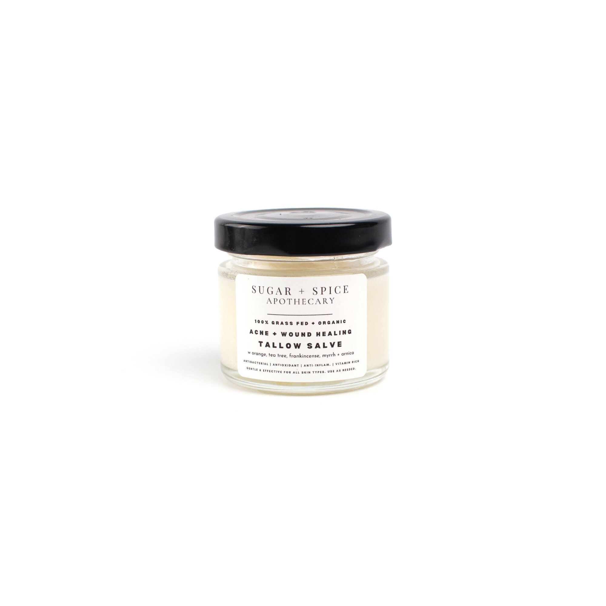 Small jar with black lid and white label, containing sugar and spice salve, on a white background.
