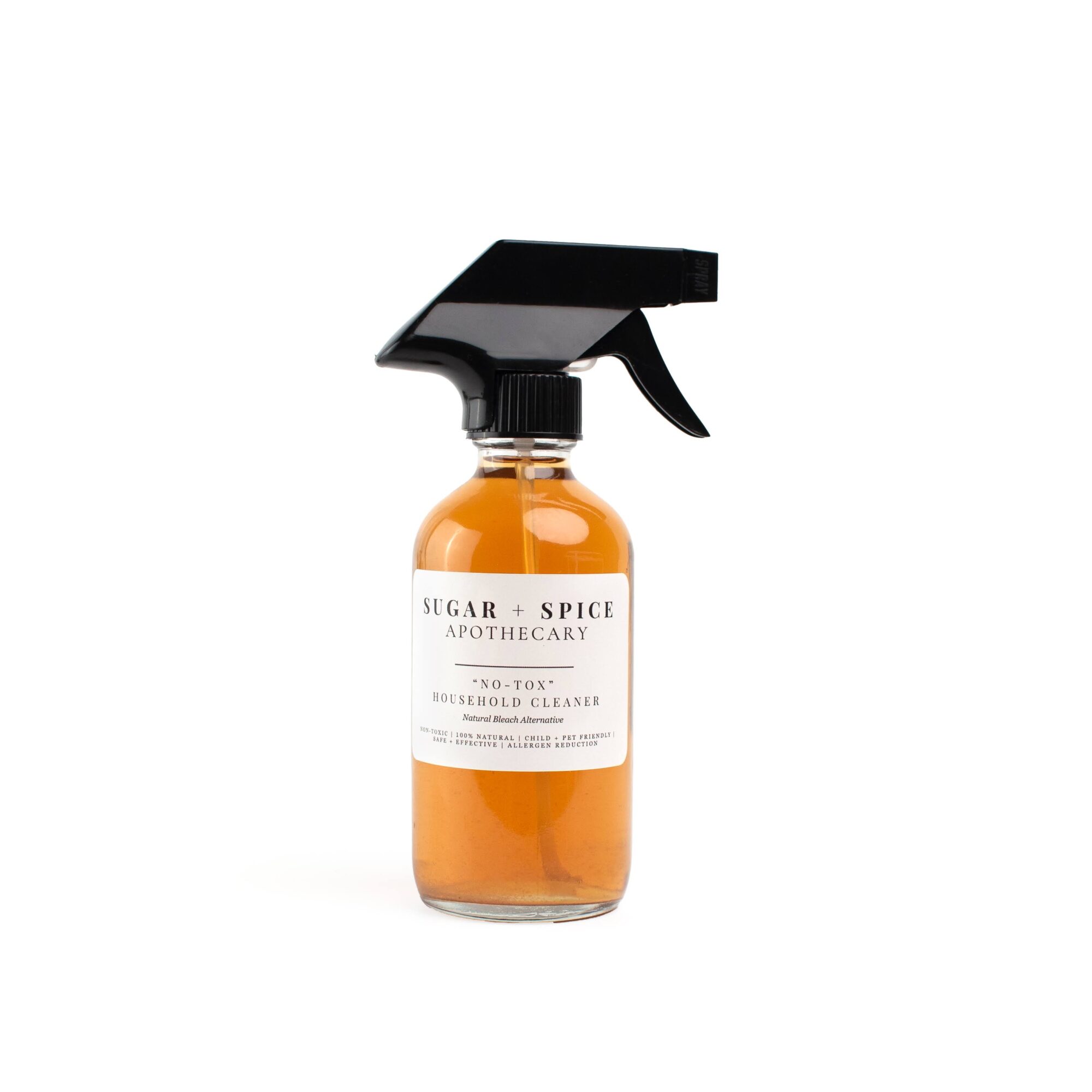 Spray bottle with orange liquid and black spray nozzle, labeled 'Sugar + Spice Apothecary'.
