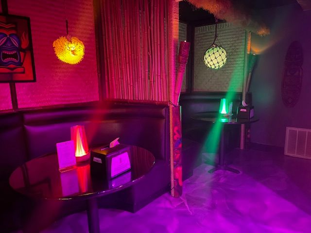 Room with colorful lighting, a curtain, and decorative lamps emitting green, yellow, and purple light.