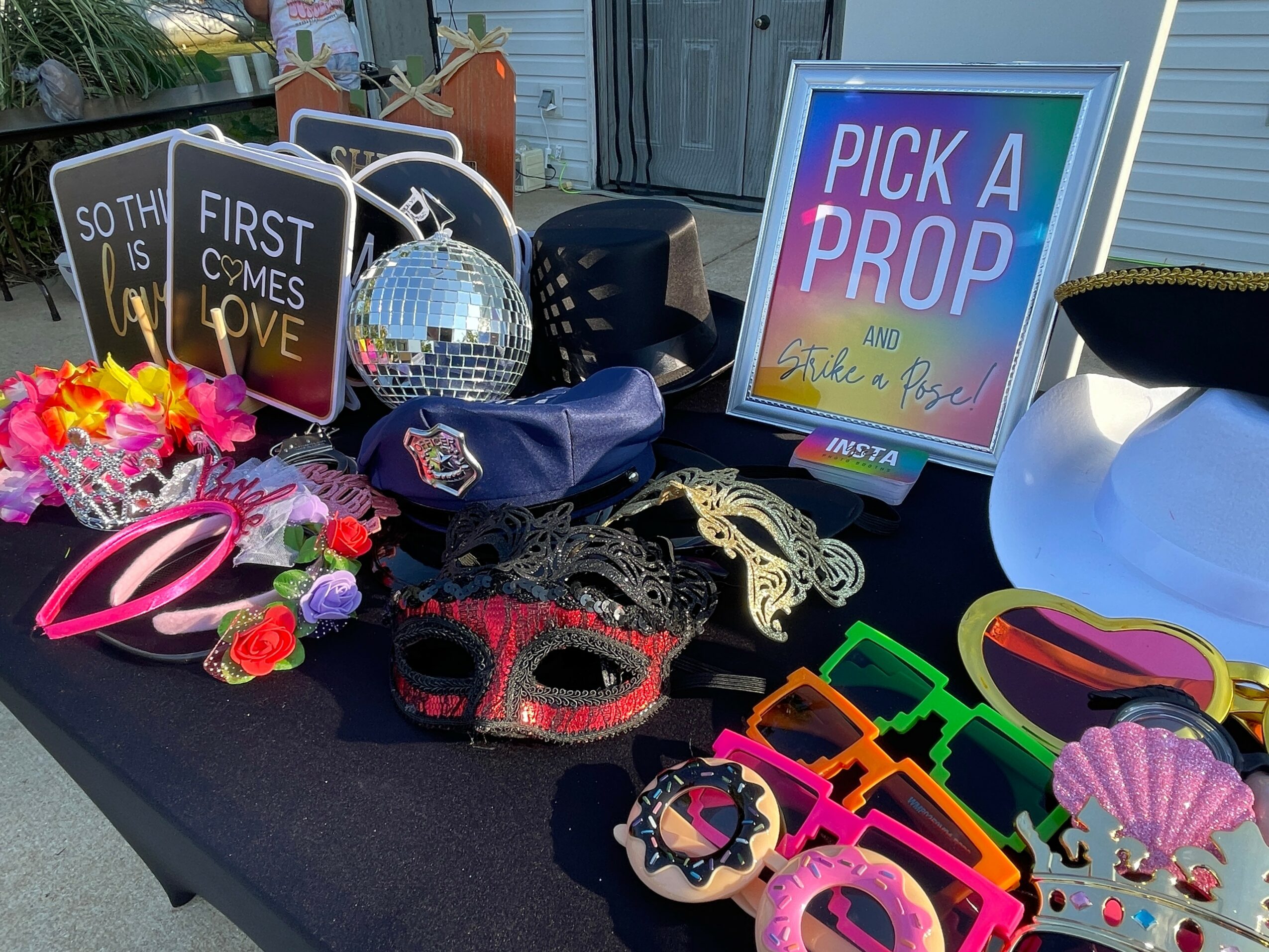 Table with colorful props including masks, glasses, hats, signs, and a sign reading 'Pick a Prop'.