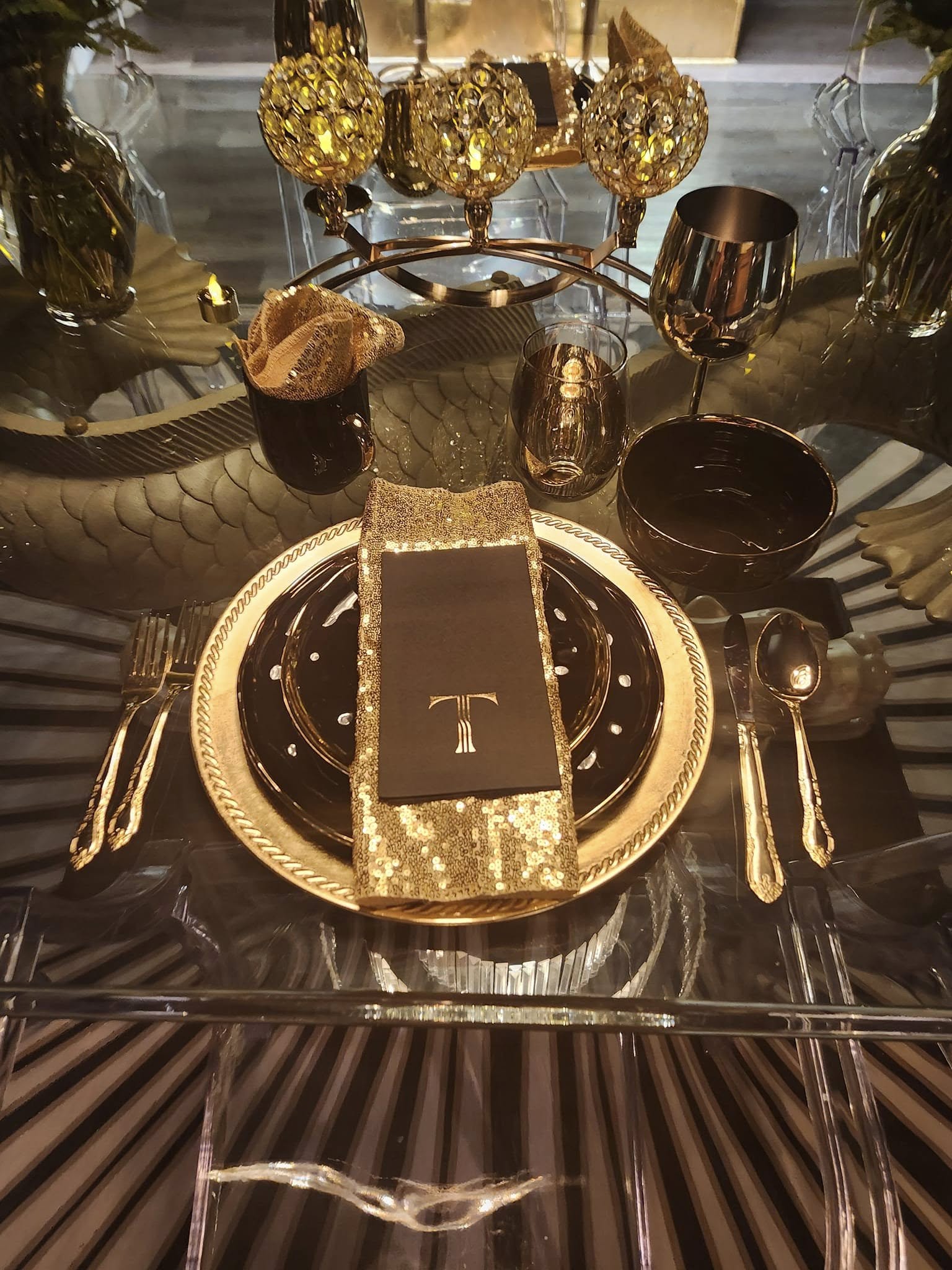 Elegant table setting with black and gold decor, a black menu, and gold accents on plates and cutlery.