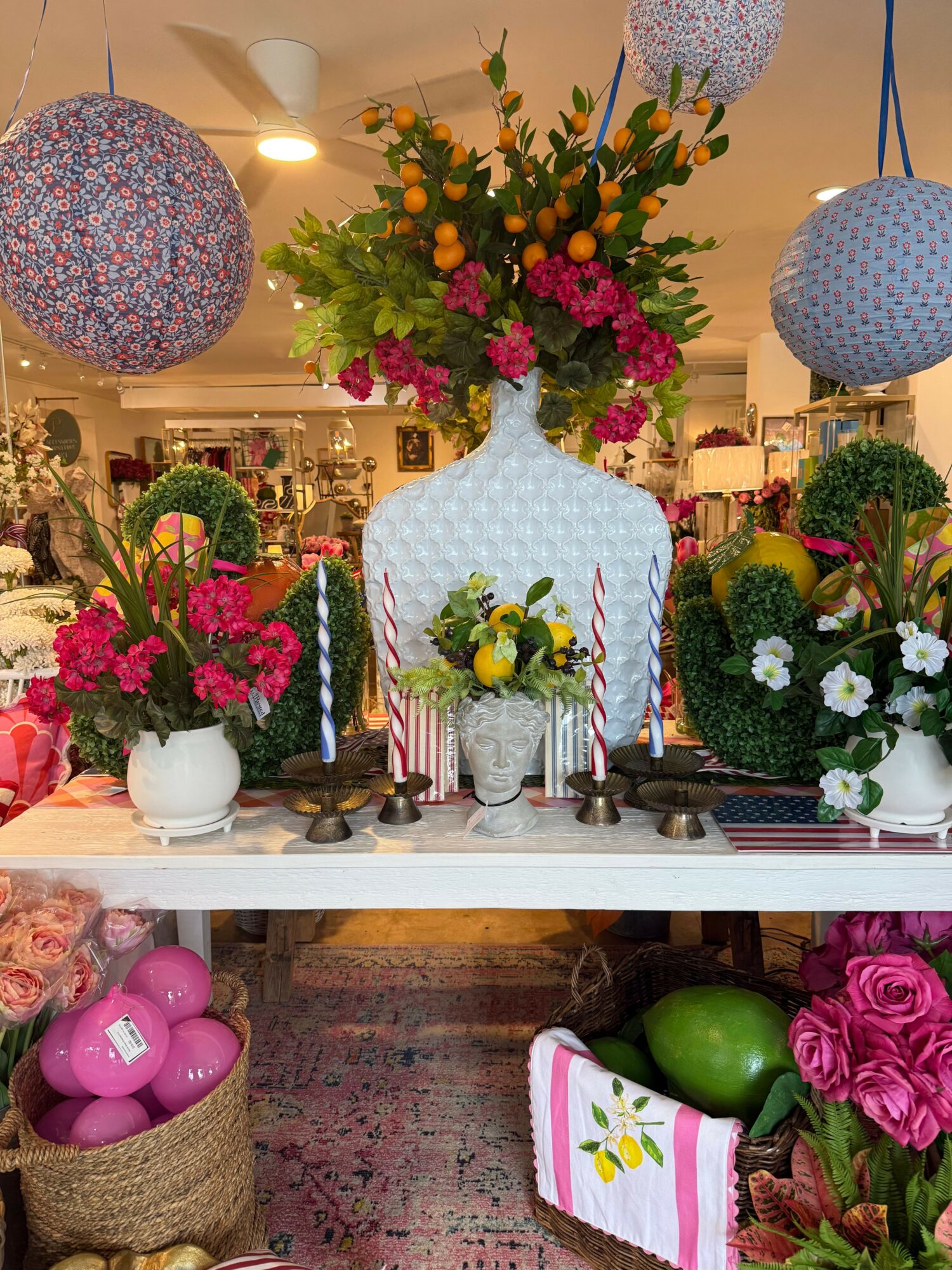 Table with colorful flower arrangements, candles, and decorative items in a cozy indoor setting.