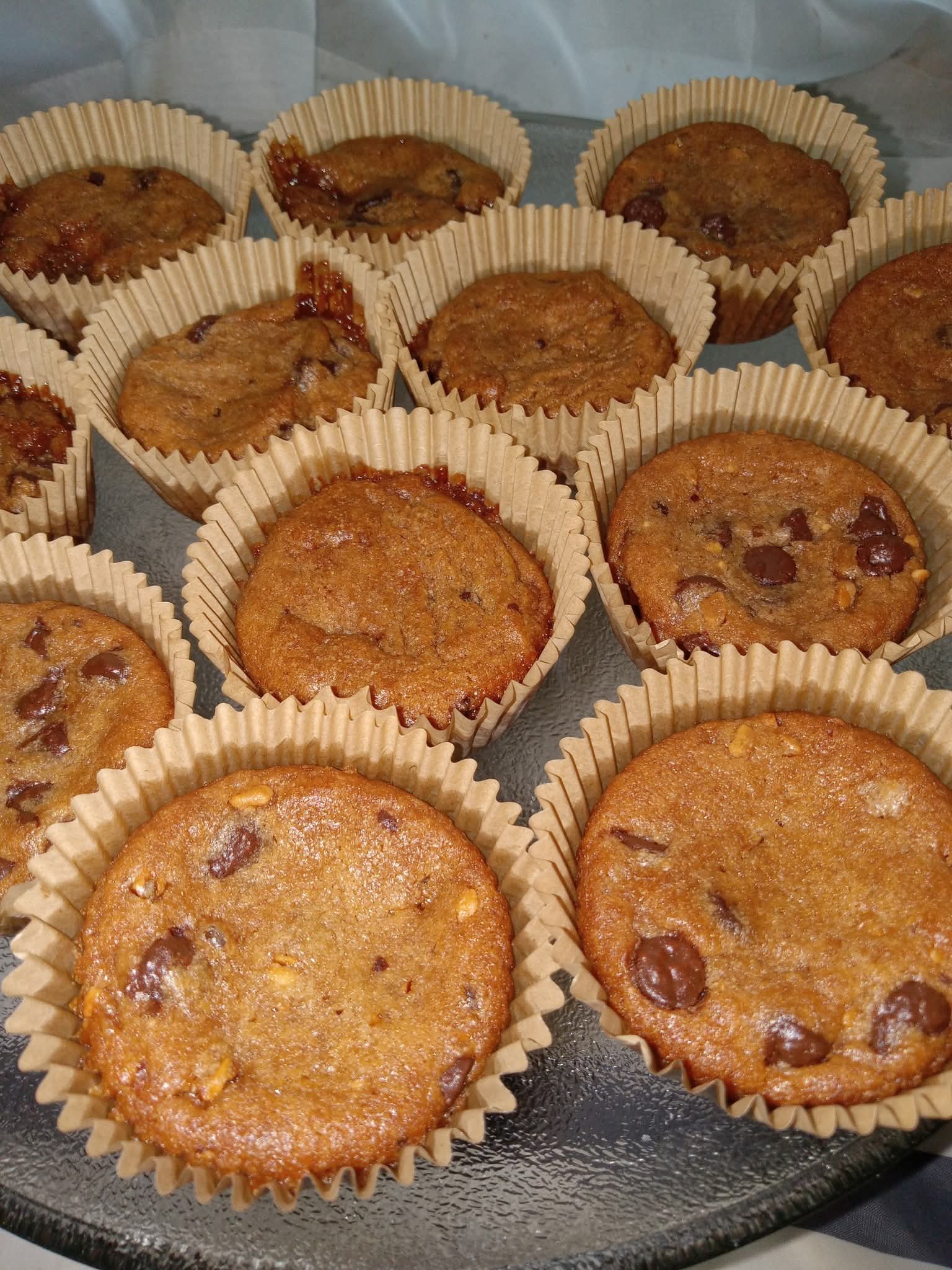 Several muffins in paper liners on a tray, some with chocolate chips, some plain, golden brown color.