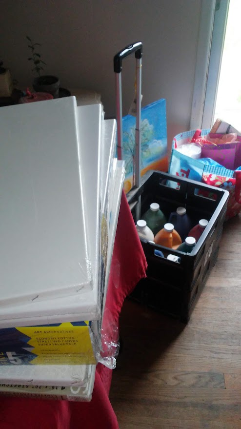 Cleaning supplies and a black crate with bottles on a wooden floor near a window.