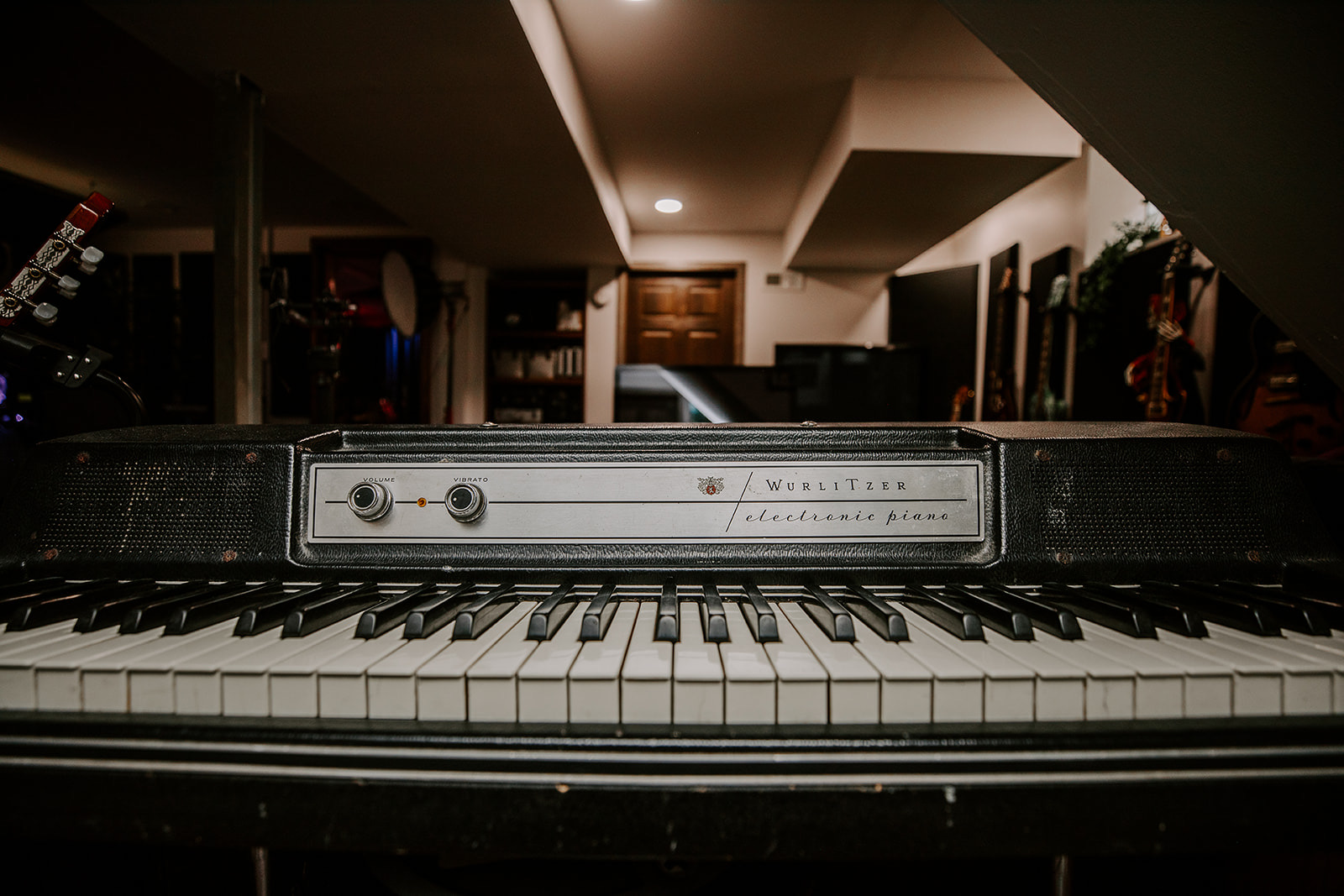Upright view of a vintage electronic keyboard with black and white keys, in a dimly lit room with shelves and furniture.