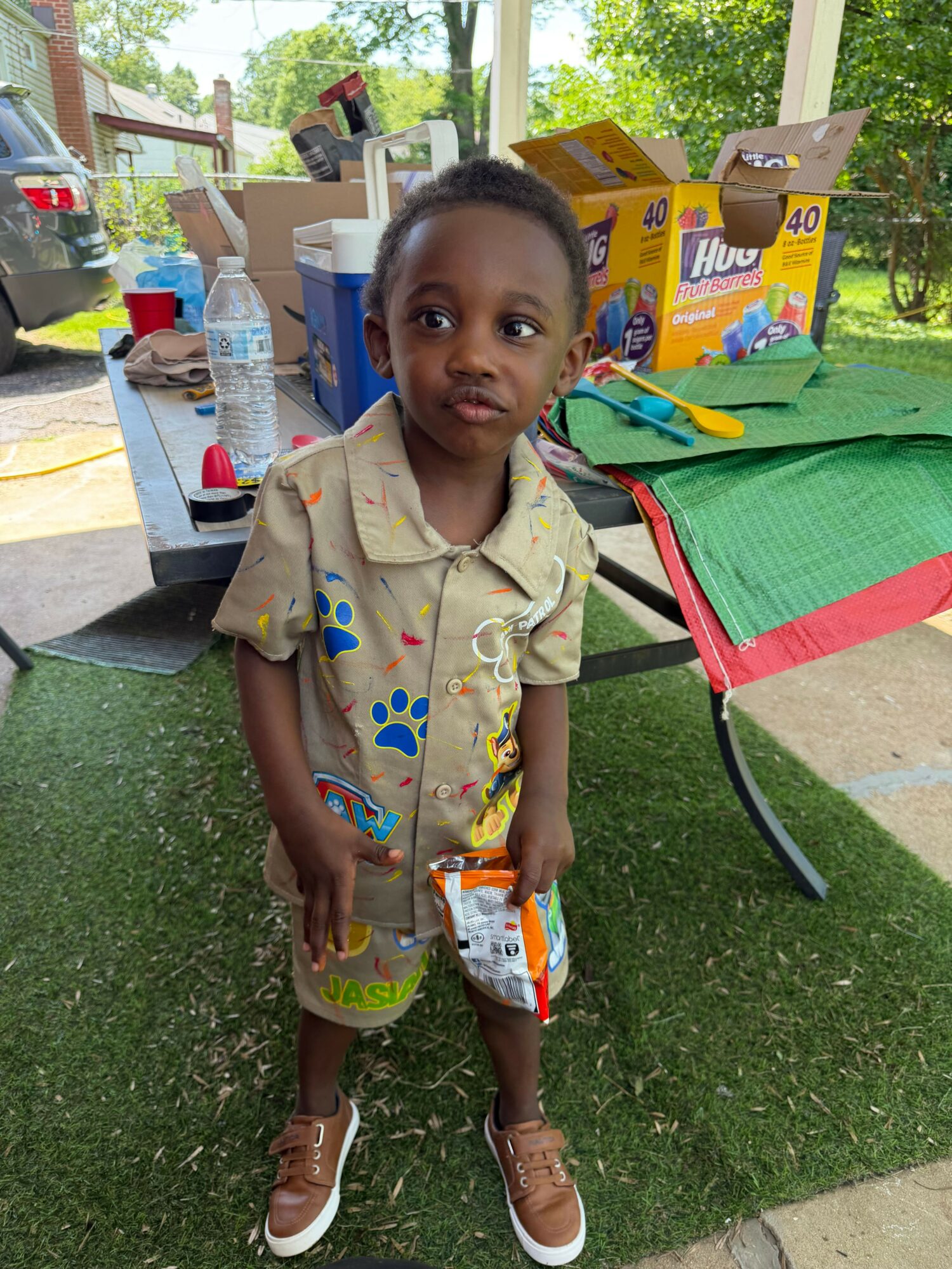 Young girl standing outdoors next to a table with boxes and supplies, smiling at the camera.