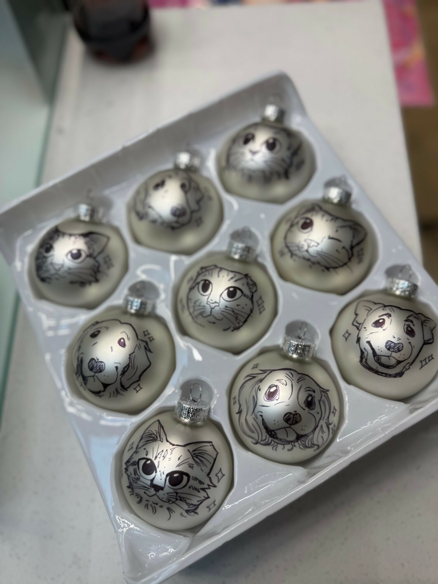 Decorative Christmas ornaments with animal faces, including a bear, cat, dog, and owl, arranged in a tray.