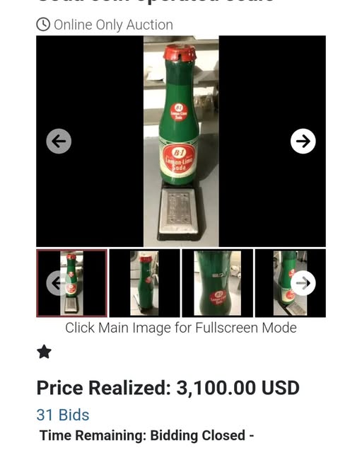 Green bottle with red and white label on a scale, viewed from the side, with black background.