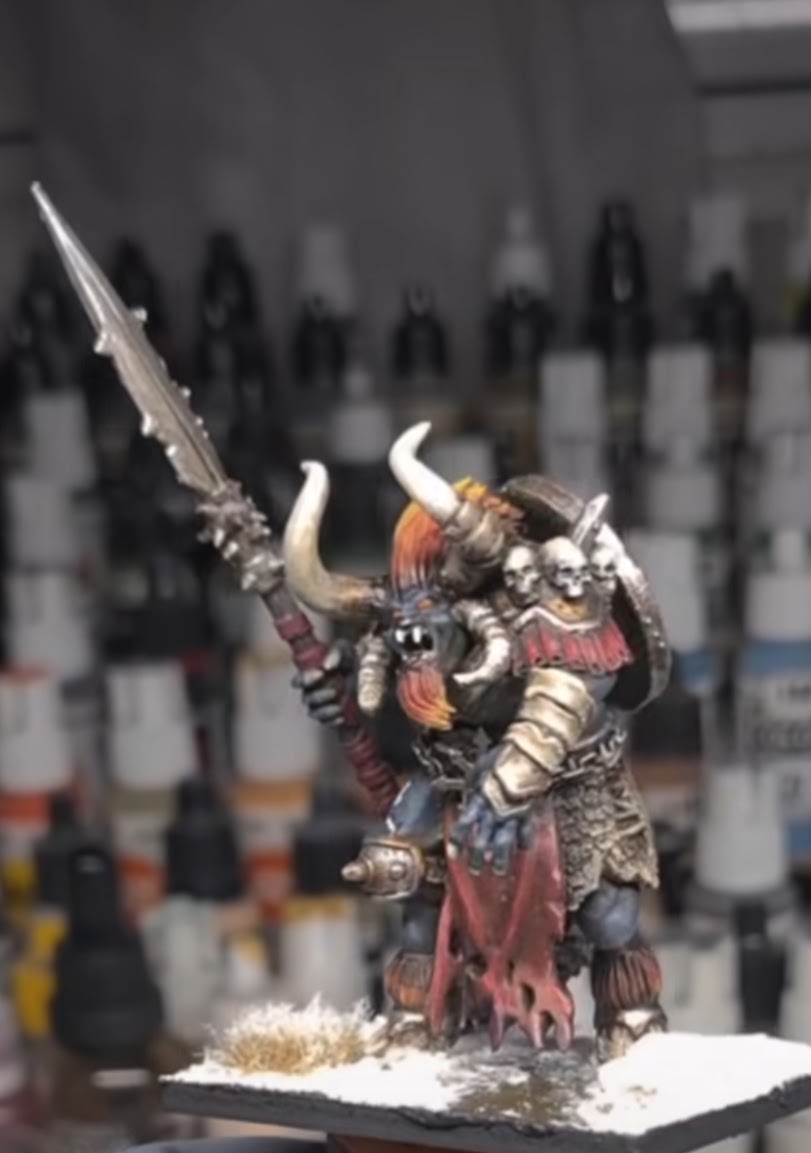 Miniature figure of a horned warrior holding a large sword, dressed in armor and a tattered cloak, on a snowy base.