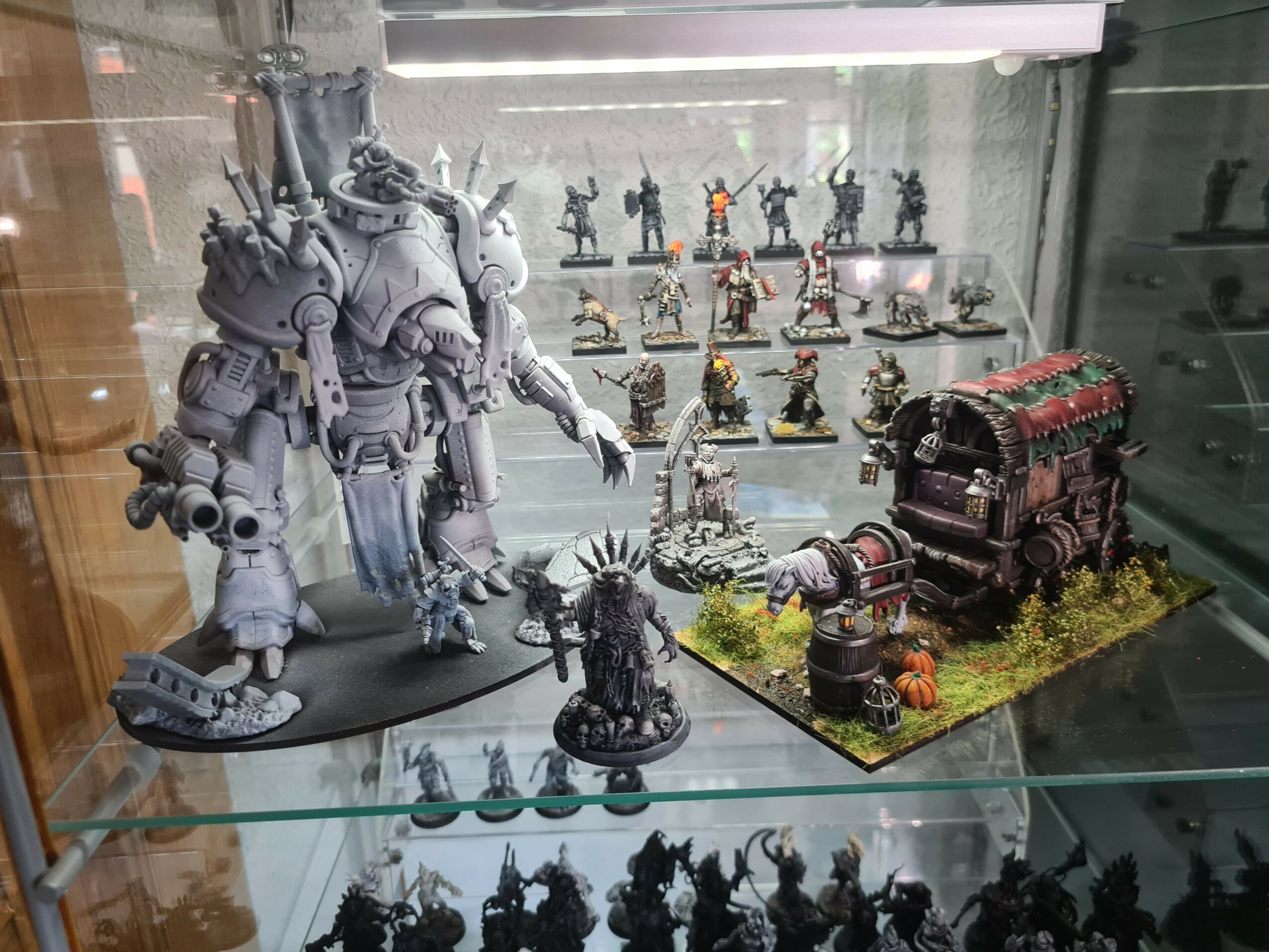 Display case with large robot figure, smaller figures, and a decorated wagon on grass-like base.
