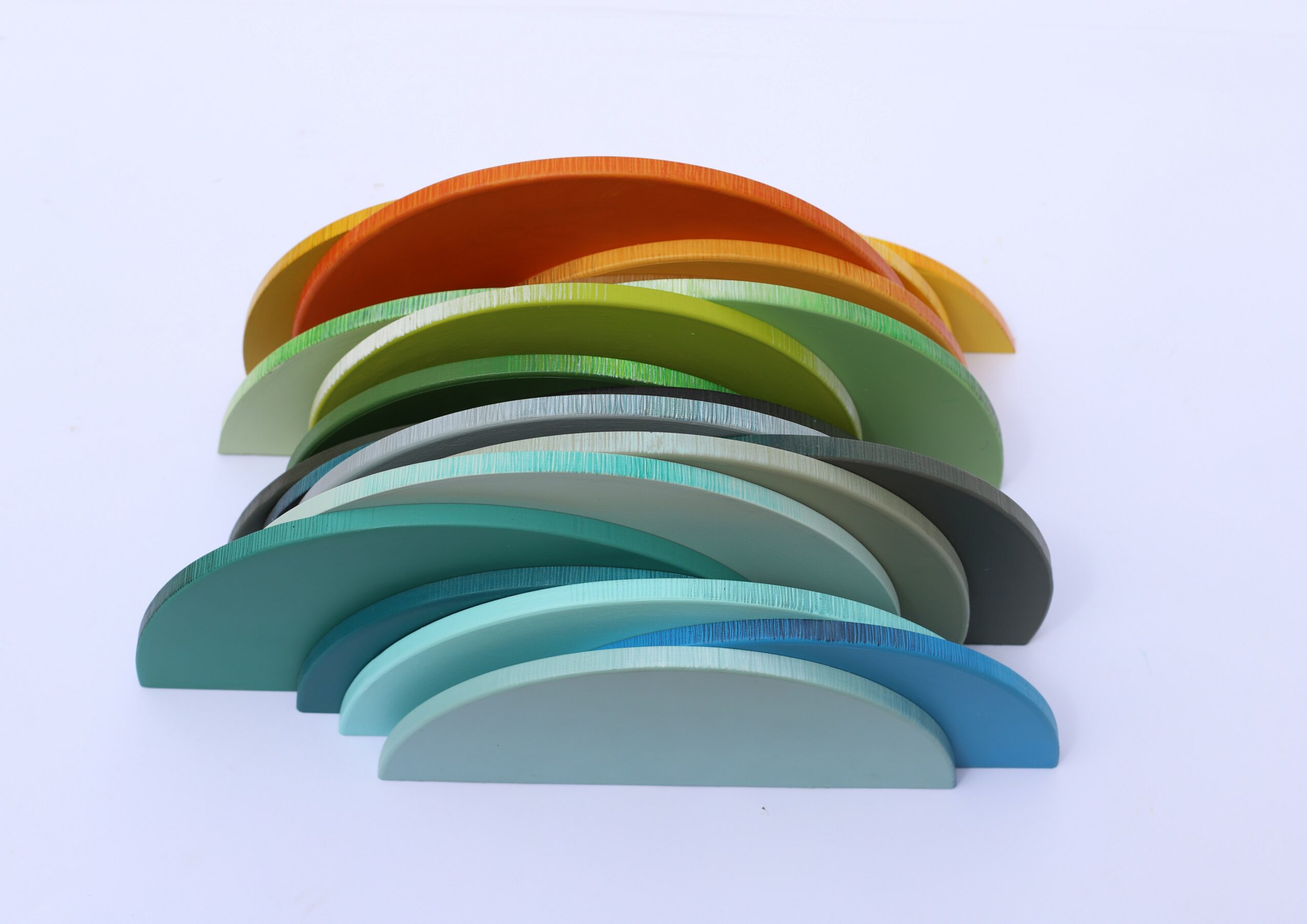 Stacked colorful plastic objects in various shades including orange, green, gray, black, and blue, arranged in a curved shape on a white background.
