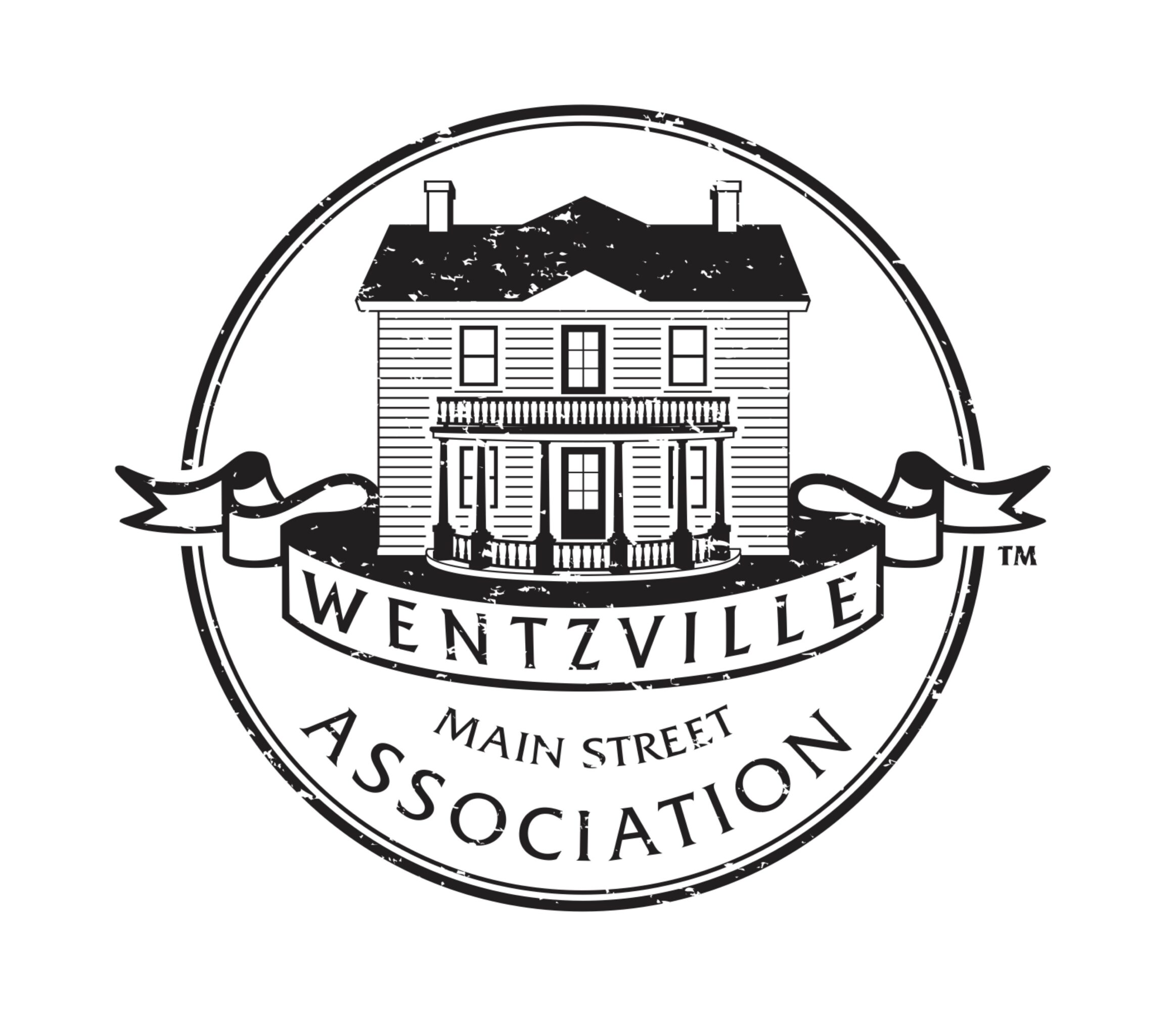 A circular logo featuring a house with a banner reading 'Wentzville Main Street Association' beneath it.