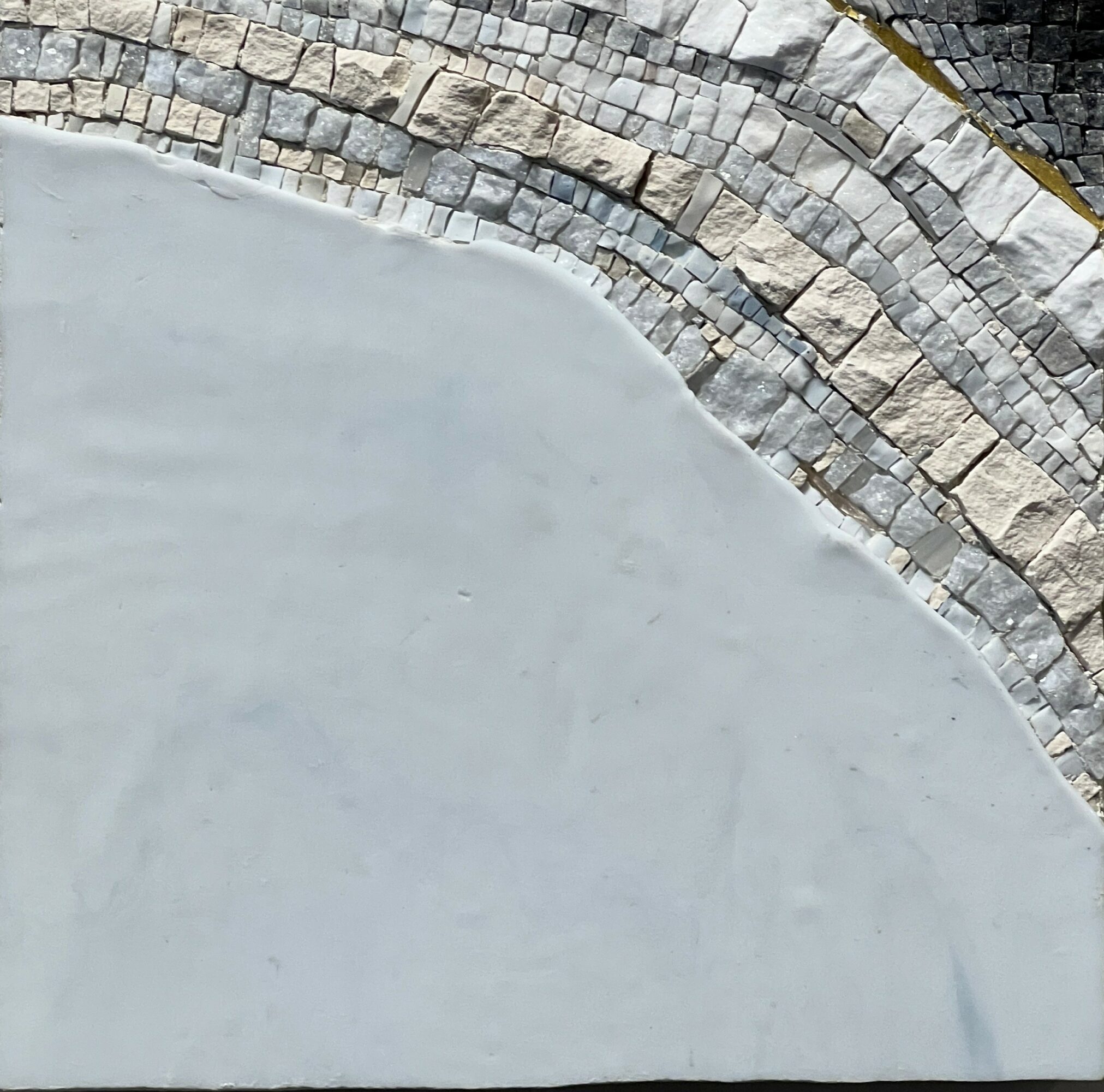 Curved stone and concrete surface with a textured stone border, viewed from above.