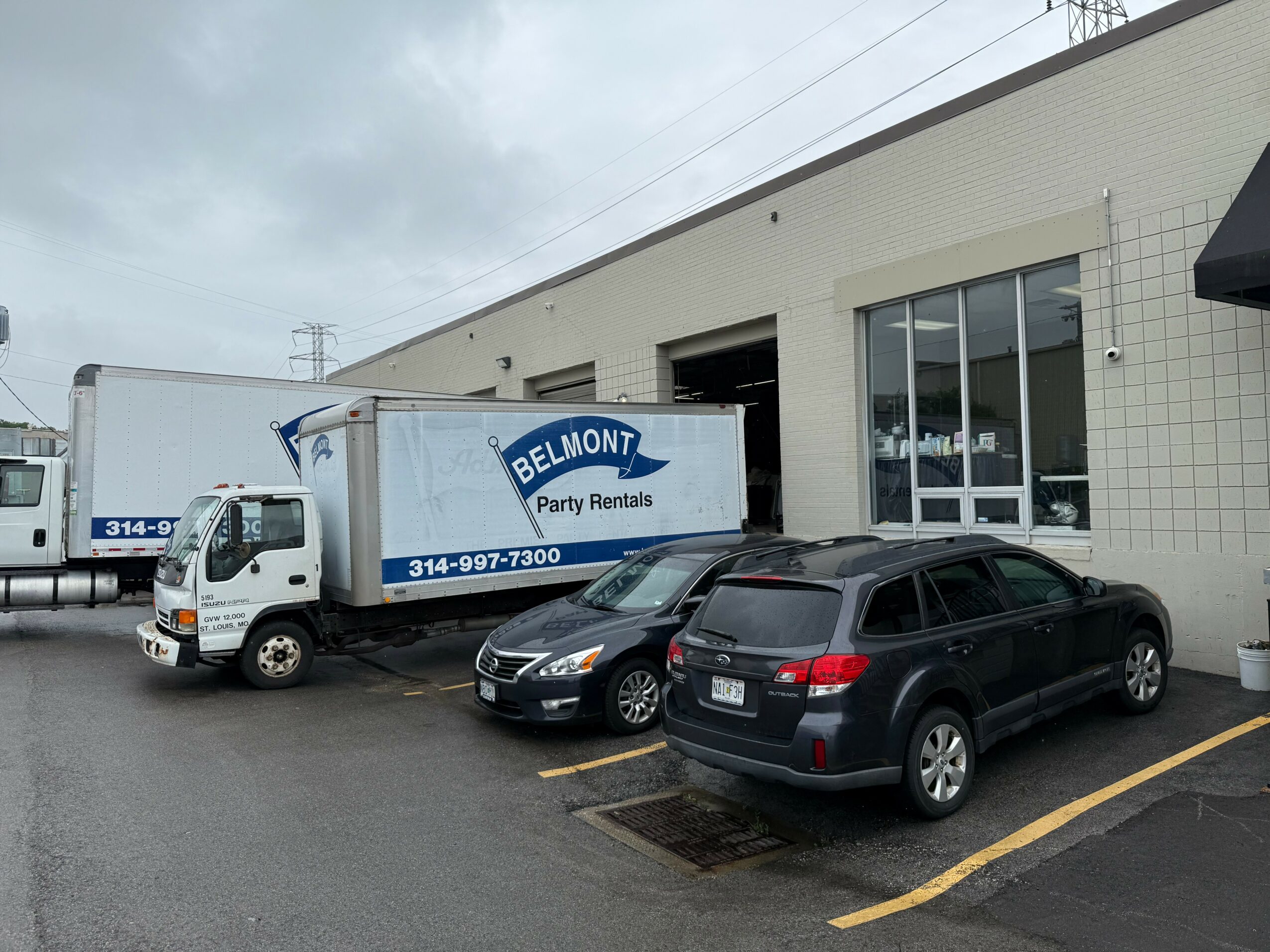 Parking lot with trucks and cars outside a building under cloudy sky.