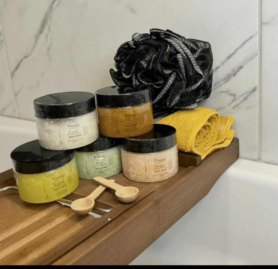 Stacked jars with black lids, a black bag, and a yellow cloth on a wooden surface against a marble wall.