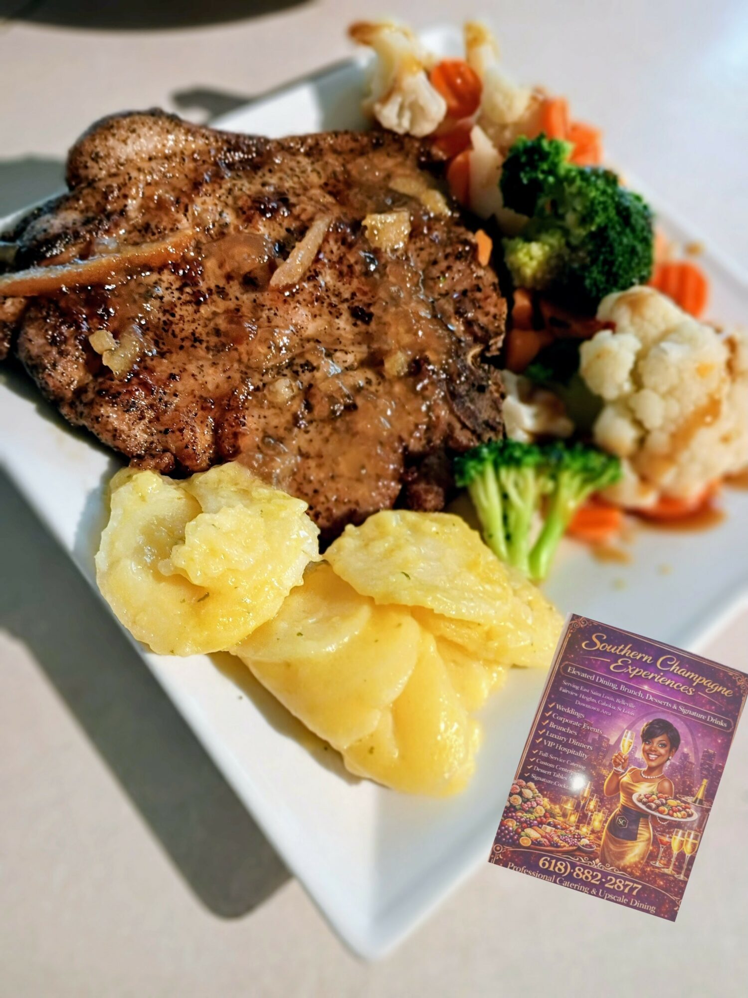 Grilled meat with mixed vegetables and mashed potatoes on a white plate, with a purple card nearby.