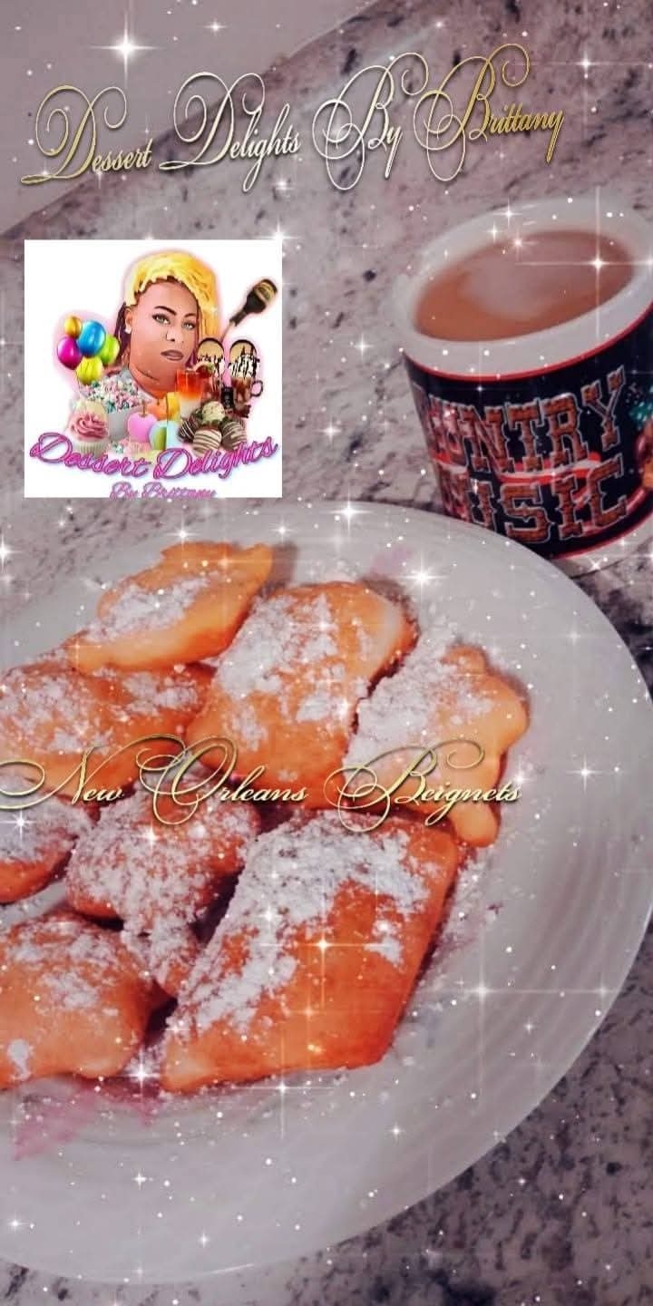 Plate of fried pastries dusted with powdered sugar next to a mug of hot chocolate on a speckled surface.