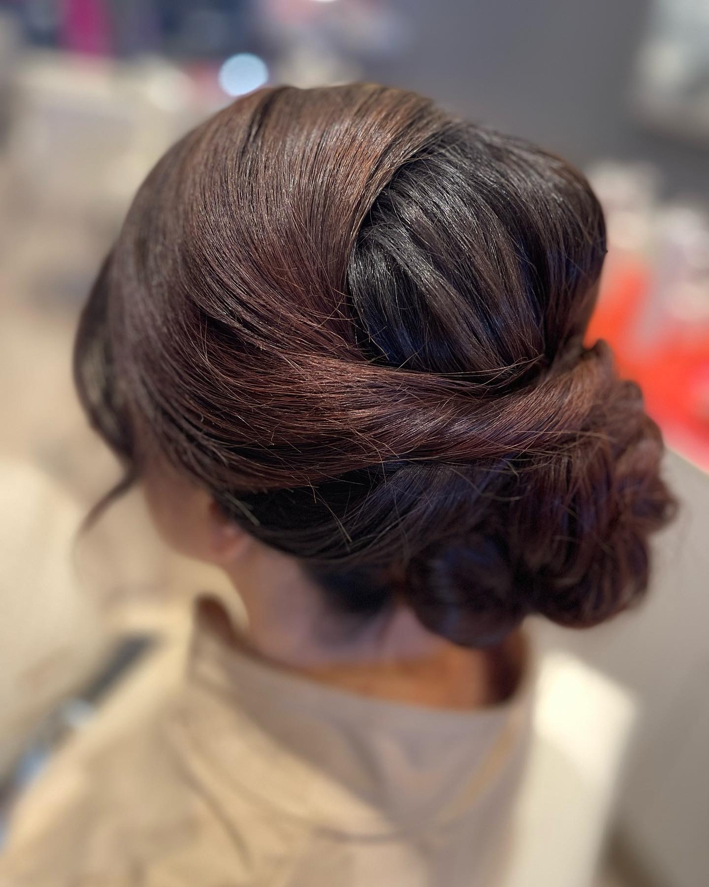 Updo hairstyle with smooth, styled hair gathered at the back, with some volume and a twist, seen from behind.