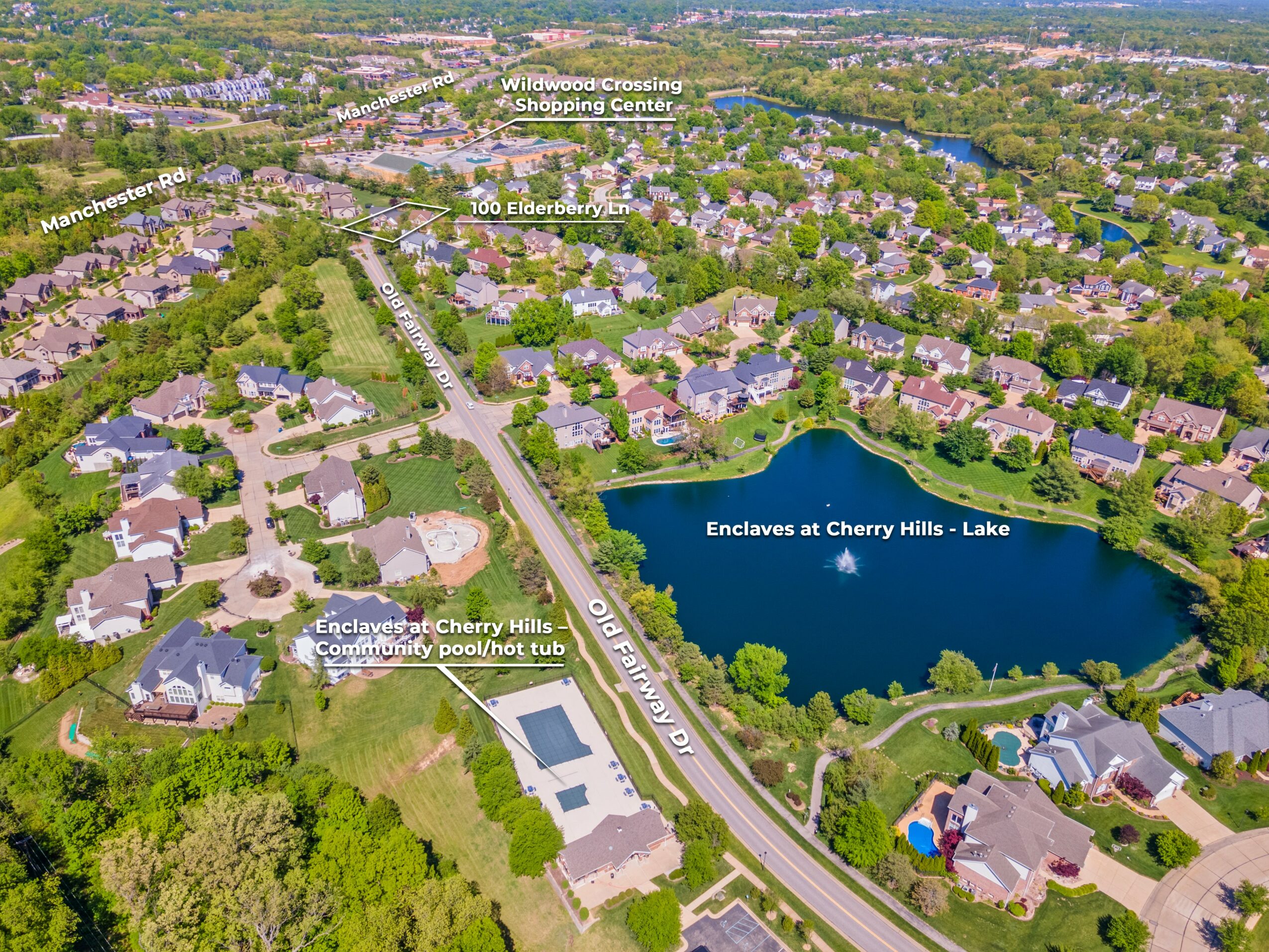 Residential neighborhood with houses, a lake, and a pool, surrounded by trees and roads.