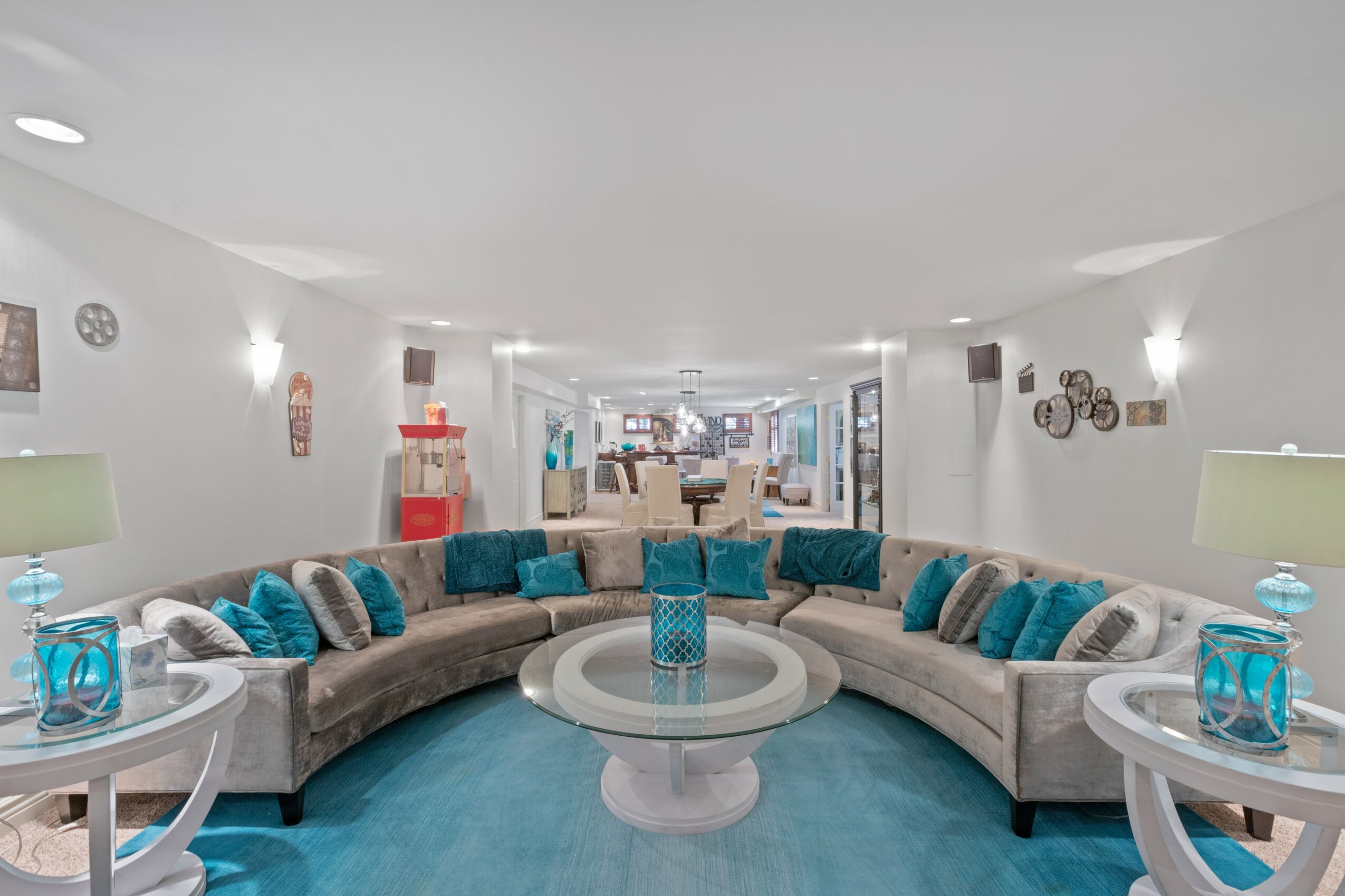 Spacious living room with a large curved sofa, two side tables with lamps, and decorative wall art, bright and airy.