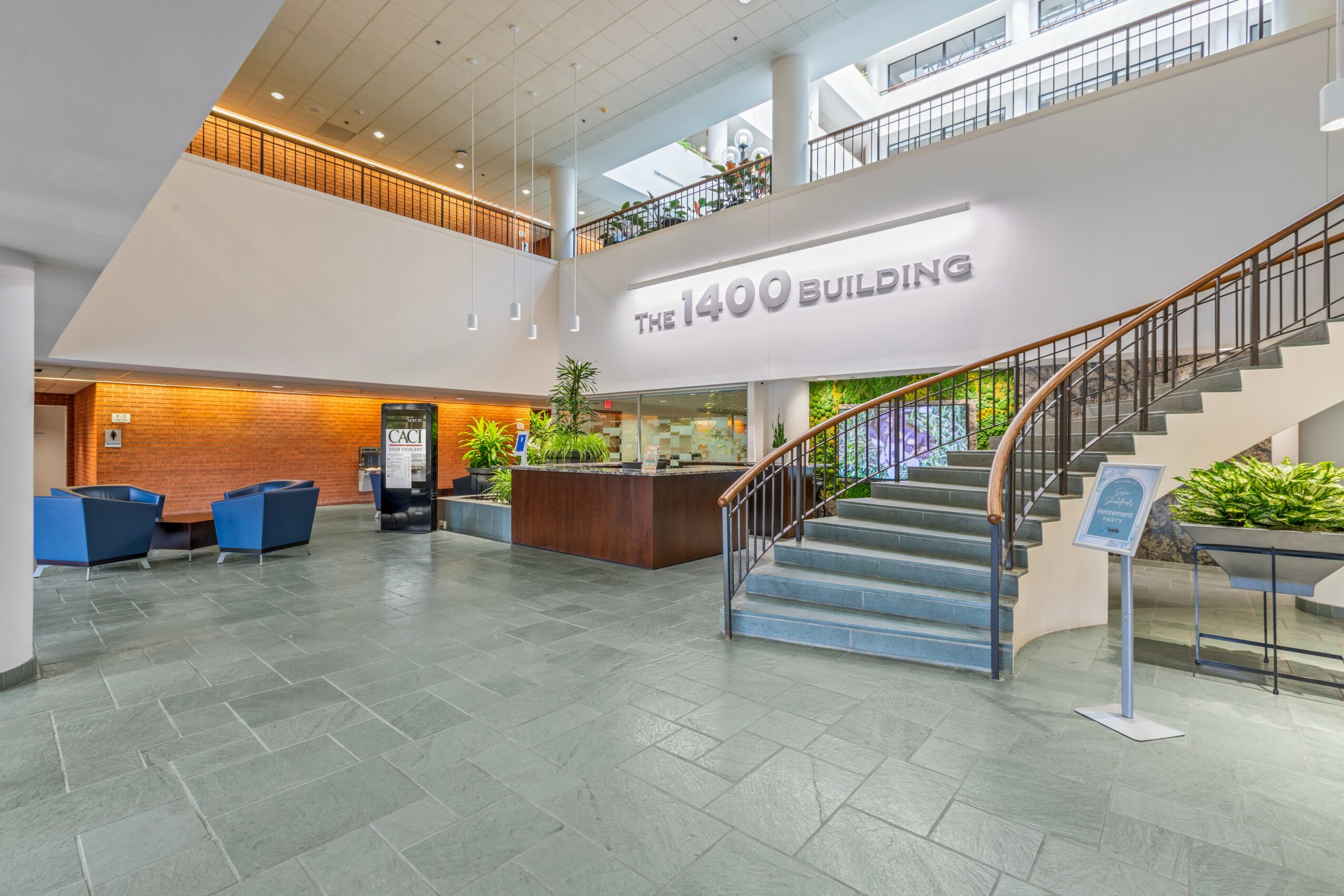 Lobby with stairs, seating, and a sign reading 'The 1400 Building' in a modern, spacious interior.