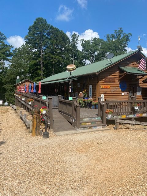 A wooden deck with outdoor furniture, American flags, and trees in the background under a blue sky.