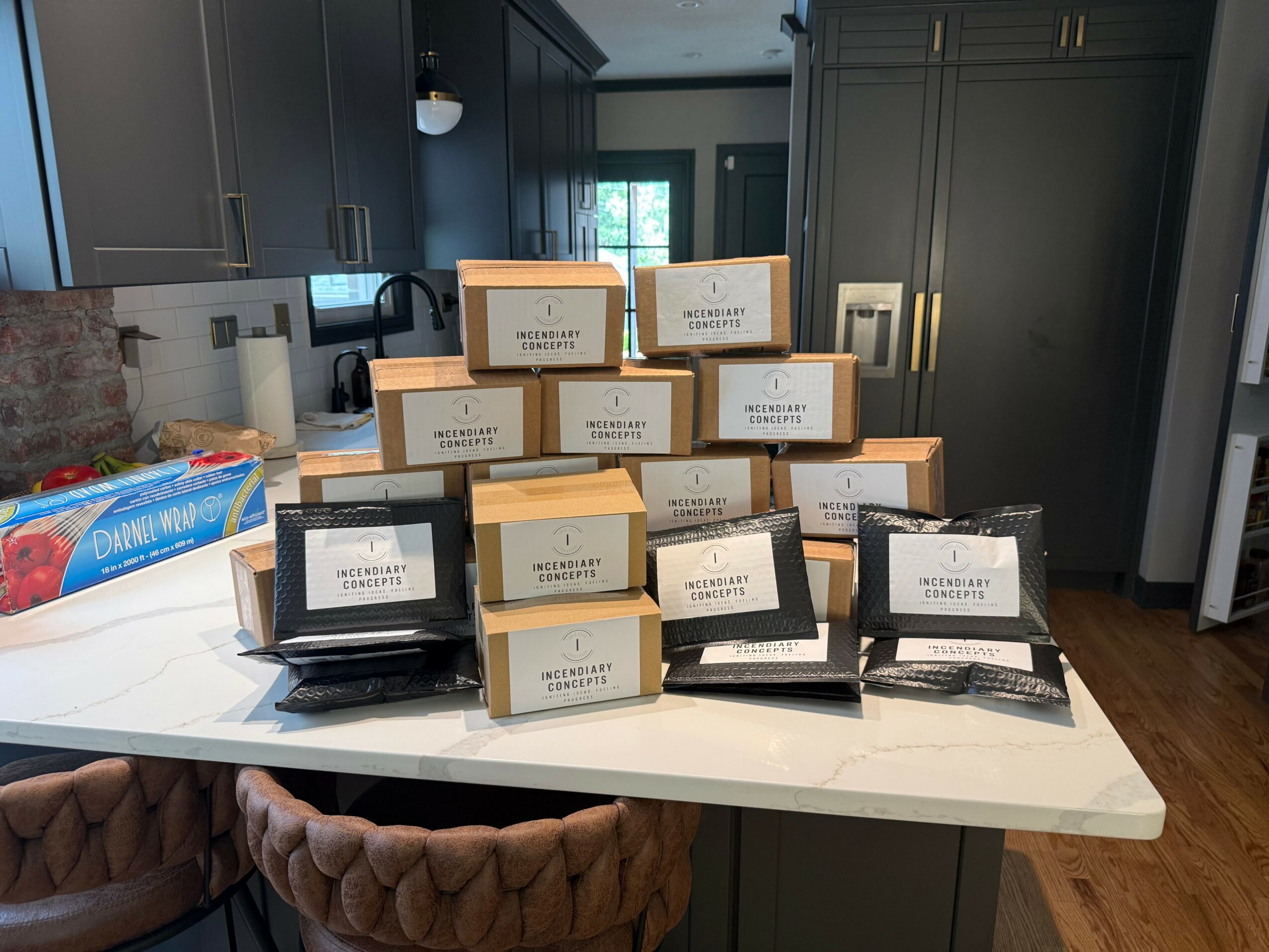 Multiple boxes and packages stacked on a kitchen island with dark cabinets in the background.