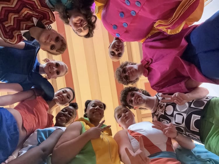 Group of people looking down at camera, smiling, in a room with striped ceiling.
