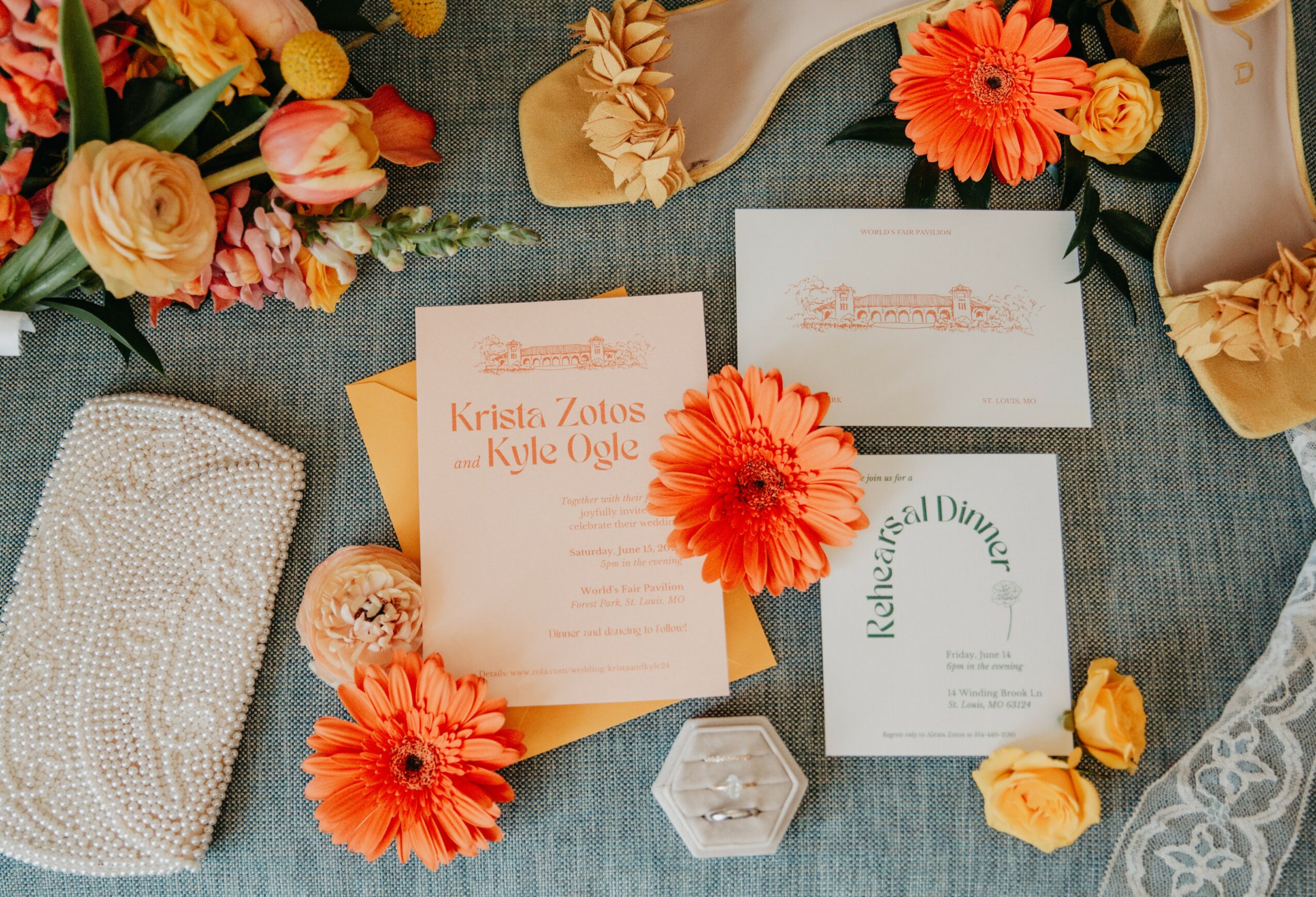 Wedding invitation cards, flowers, and accessories arranged on a table, with a lace fabric visible on the right side.