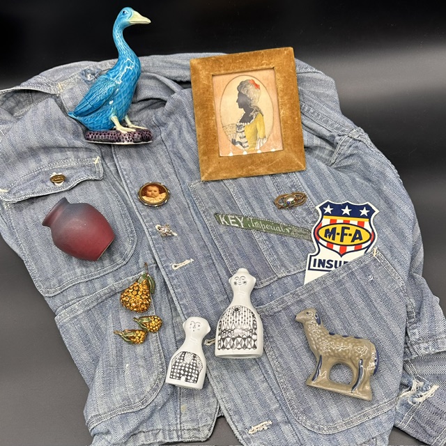 A denim jacket with various pins, a framed silhouette, a blue bird figurine, and a small horse figurine.