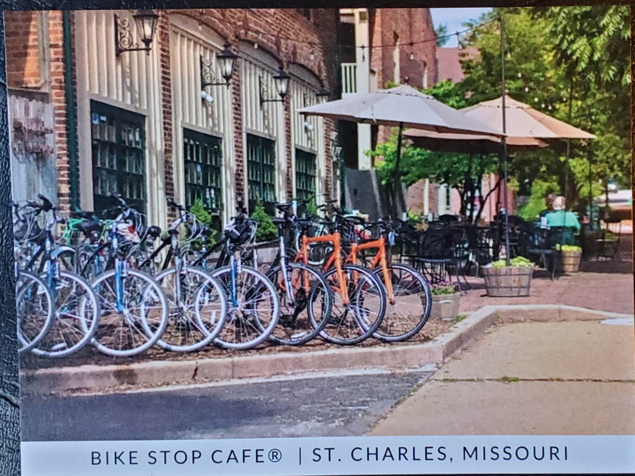 Bicycles parked outside a cafe with outdoor seating and umbrellas, in St. Charles, Missouri.