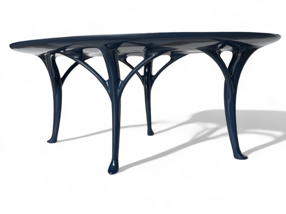 A black, modern table with a unique, sculptural base and a smooth, oval top.