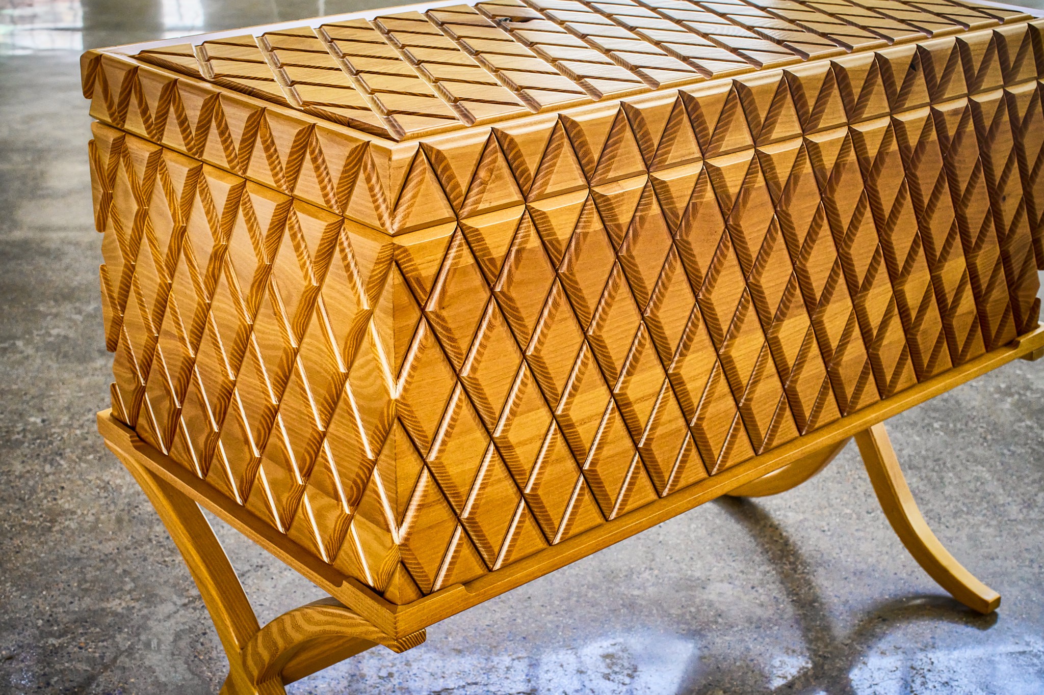 Decorative wooden cabinet with diamond pattern, curved legs, and a textured top surface.