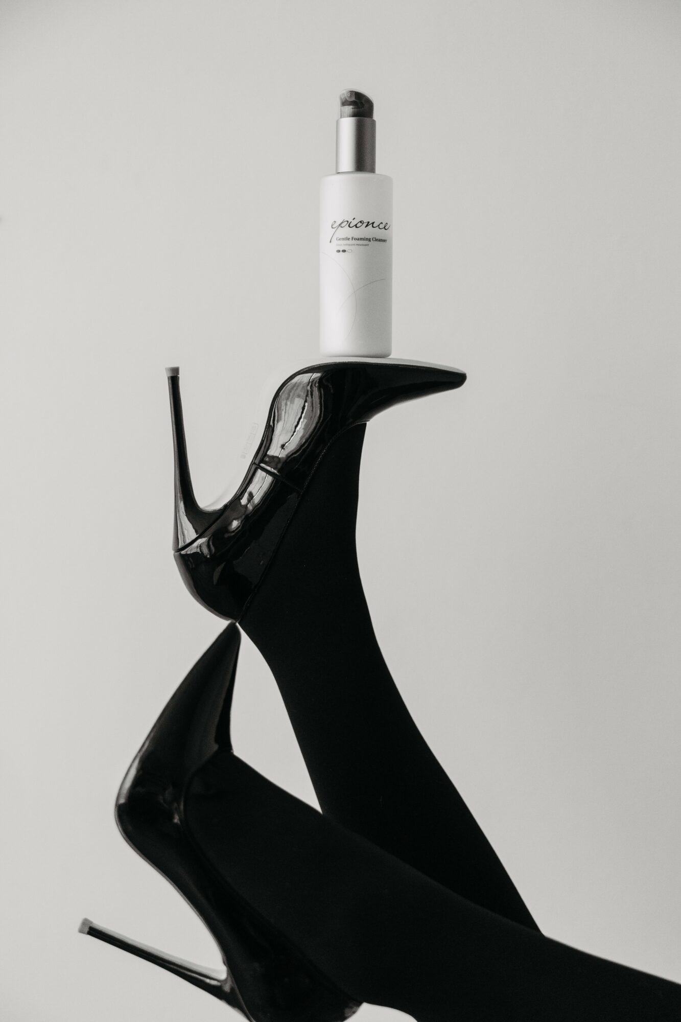 A black robotic hand holding a white device upright against a plain background.