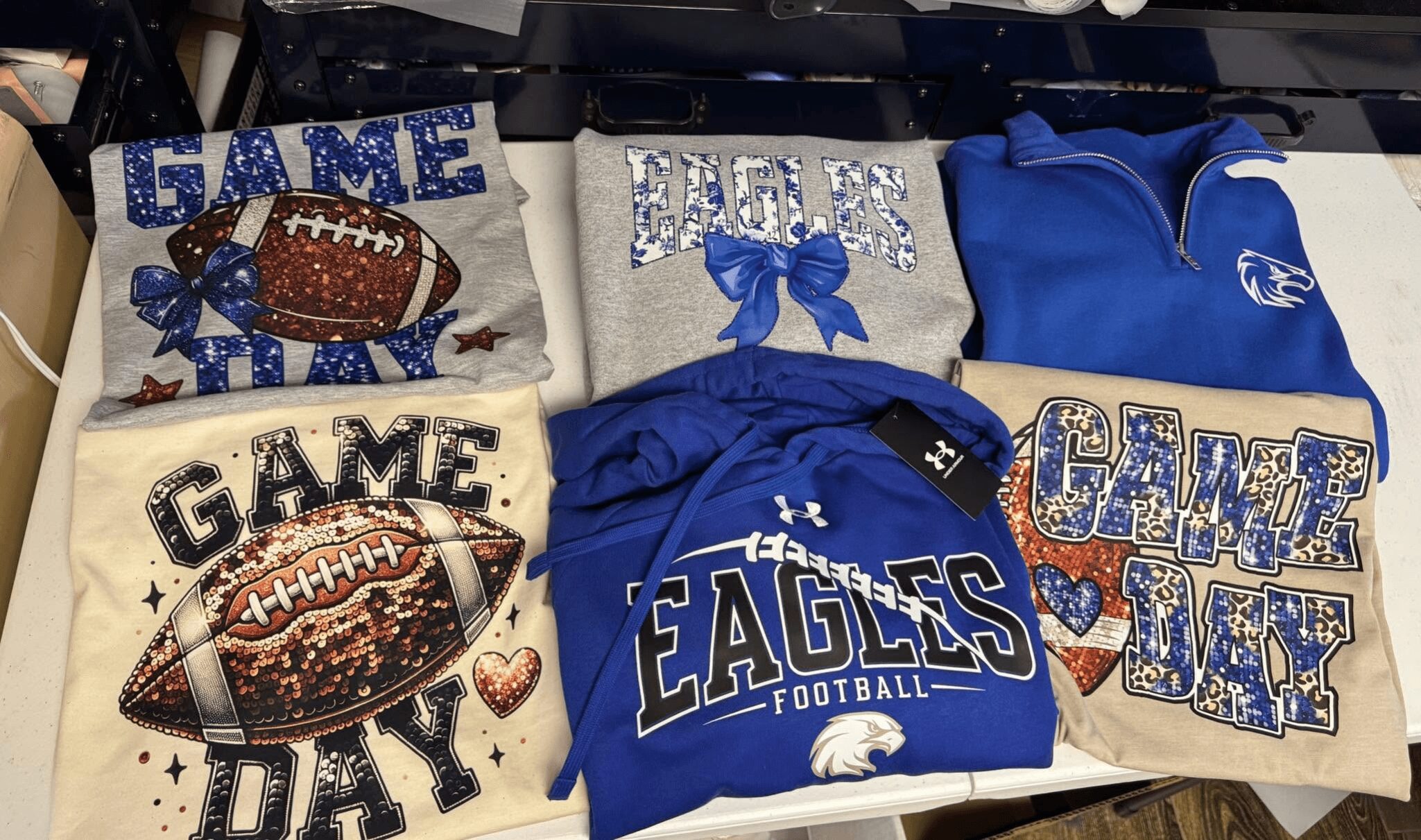 Six items with football and Eagles themes, including pillows, shirts, and a towel, arranged on a surface.