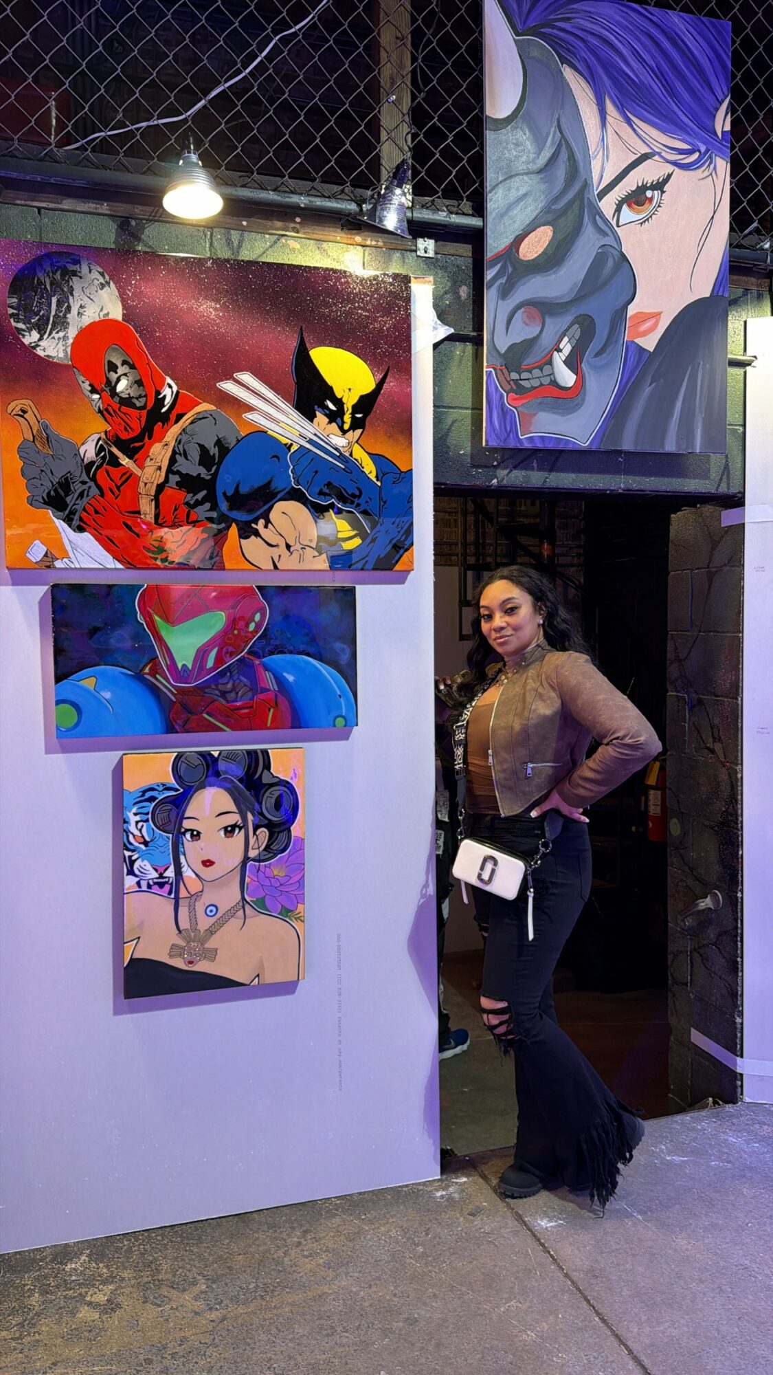 Woman standing next to colorful anime-style artwork on display at an art event.