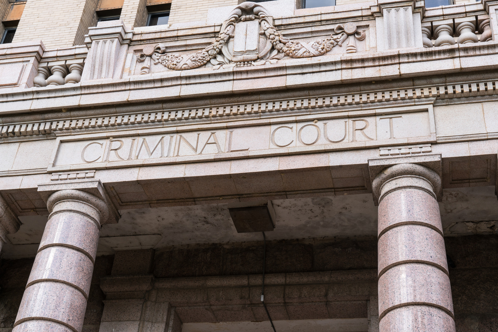 Facade of a building with columns and a sign reading 'CRIMINAL COURT'.