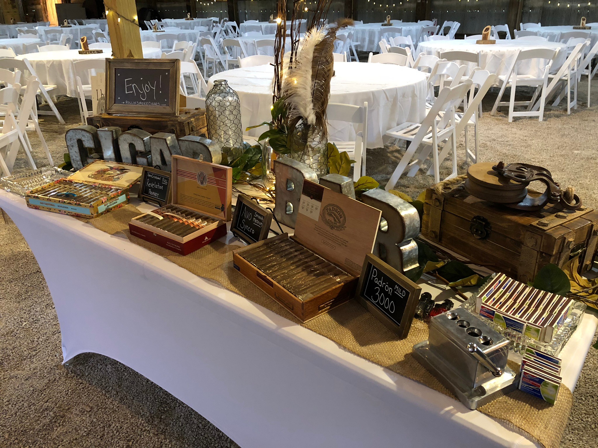 Table with vintage radios, books, and decorative items at an outdoor event, with empty white chairs and tables in background.