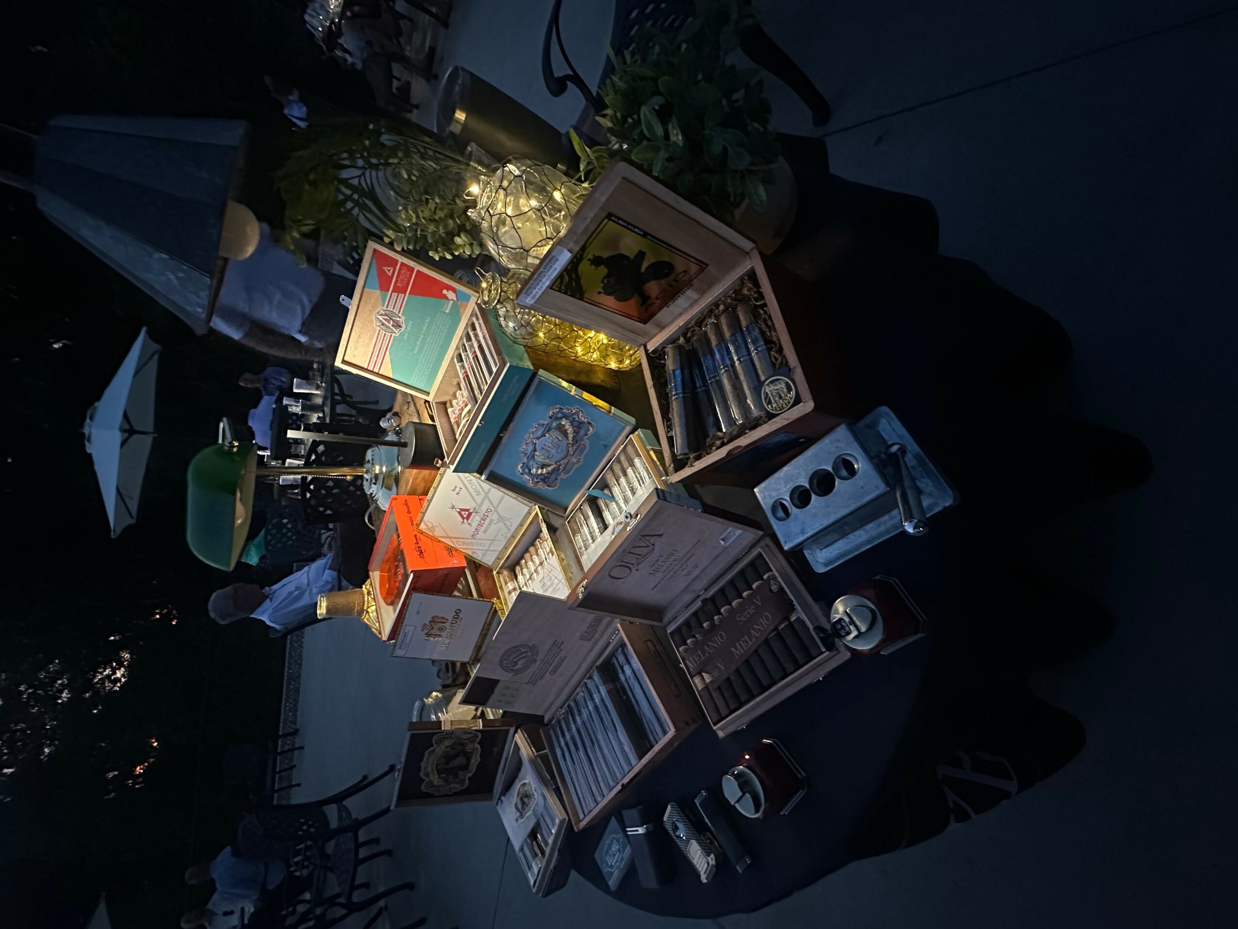 A table with various board games and boxes, some open, in a dimly lit environment.